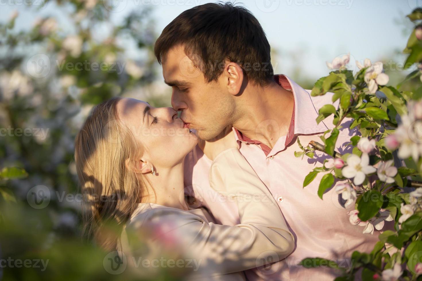 jong gelukkig paar in liefde buitenshuis. liefhebbend Mens en vrouw Aan een wandelen in een voorjaar bloeiend park foto