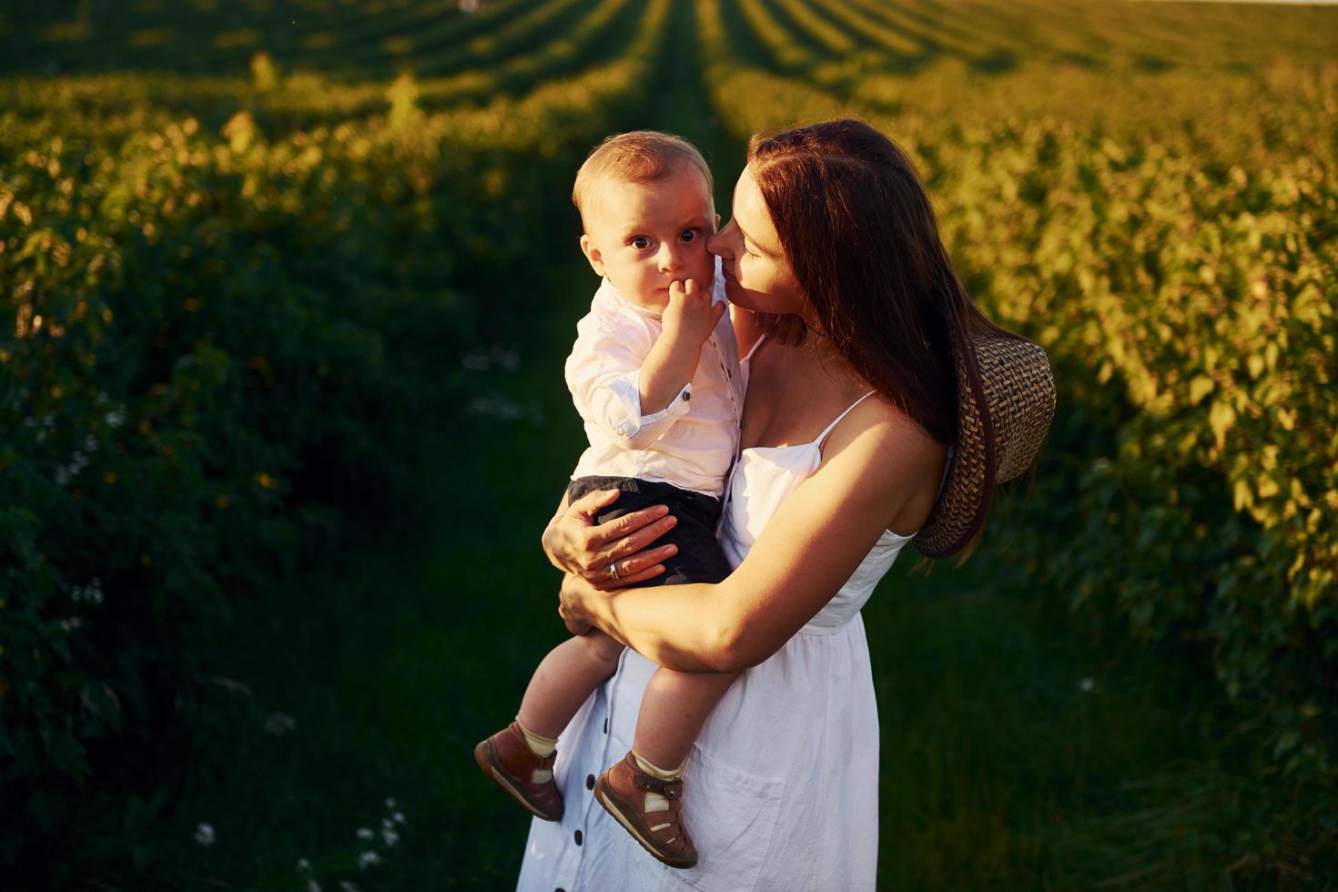 positief moeder met haar zoon uitgeven vrij tijd Aan de veld- Bij zonnig dag tijd van zomer foto