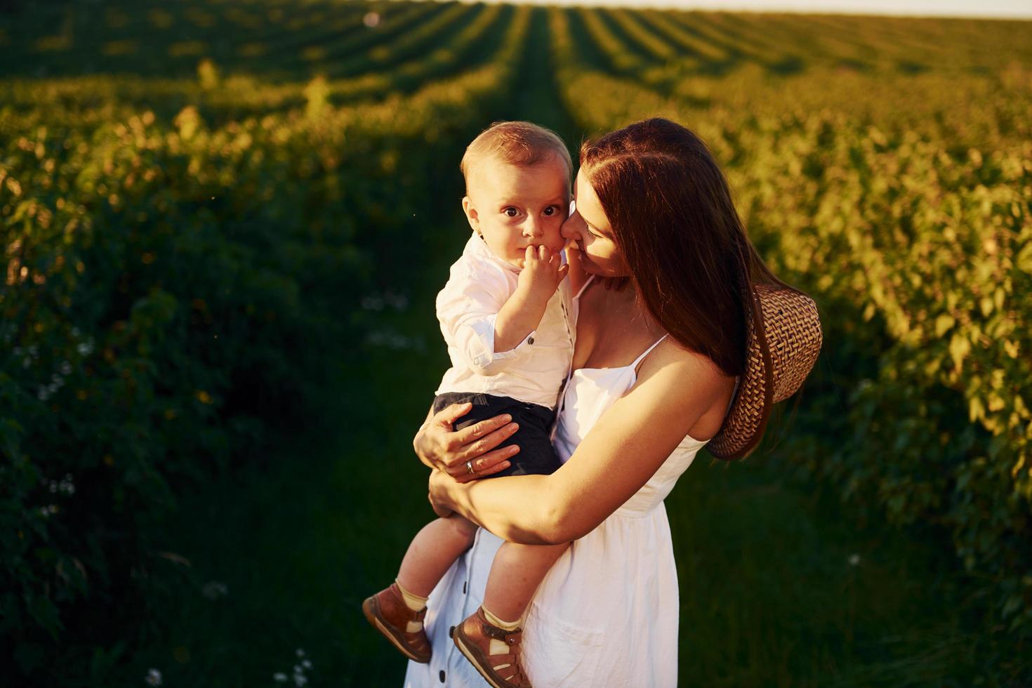 positief moeder met haar zoon uitgeven vrij tijd Aan de veld- Bij zonnig dag tijd van zomer foto