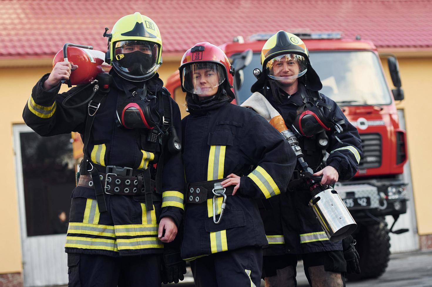 groep van brandweerlieden in beschermend uniform dat buitenshuis in de buurt vrachtauto foto