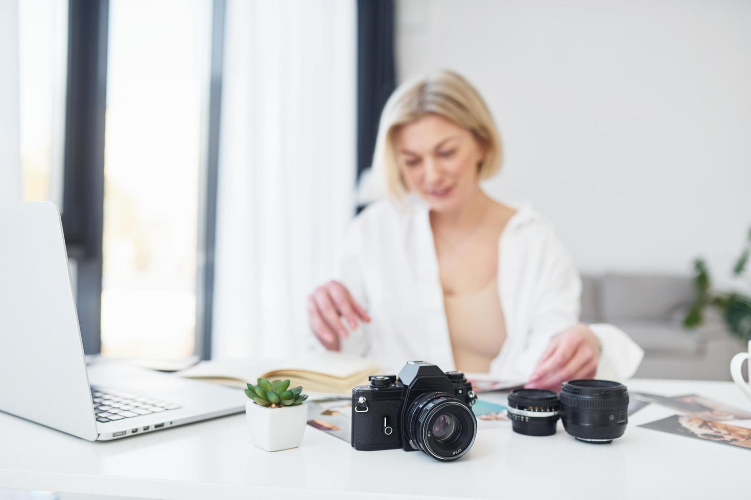 middelbare leeftijd vrouw in elegant kleren is Bij huis. fotograaf met camera foto