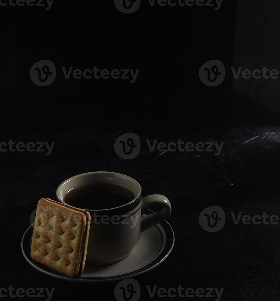 zwart koffie en biscuits Aan de zwart achtergrond foto