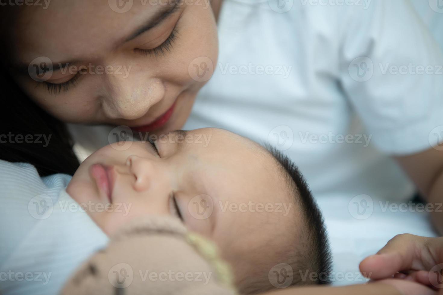 jong moeder knuffelen haar pasgeboren kind naar wiegen de baby naar slaap in de wit slaapkamer foto