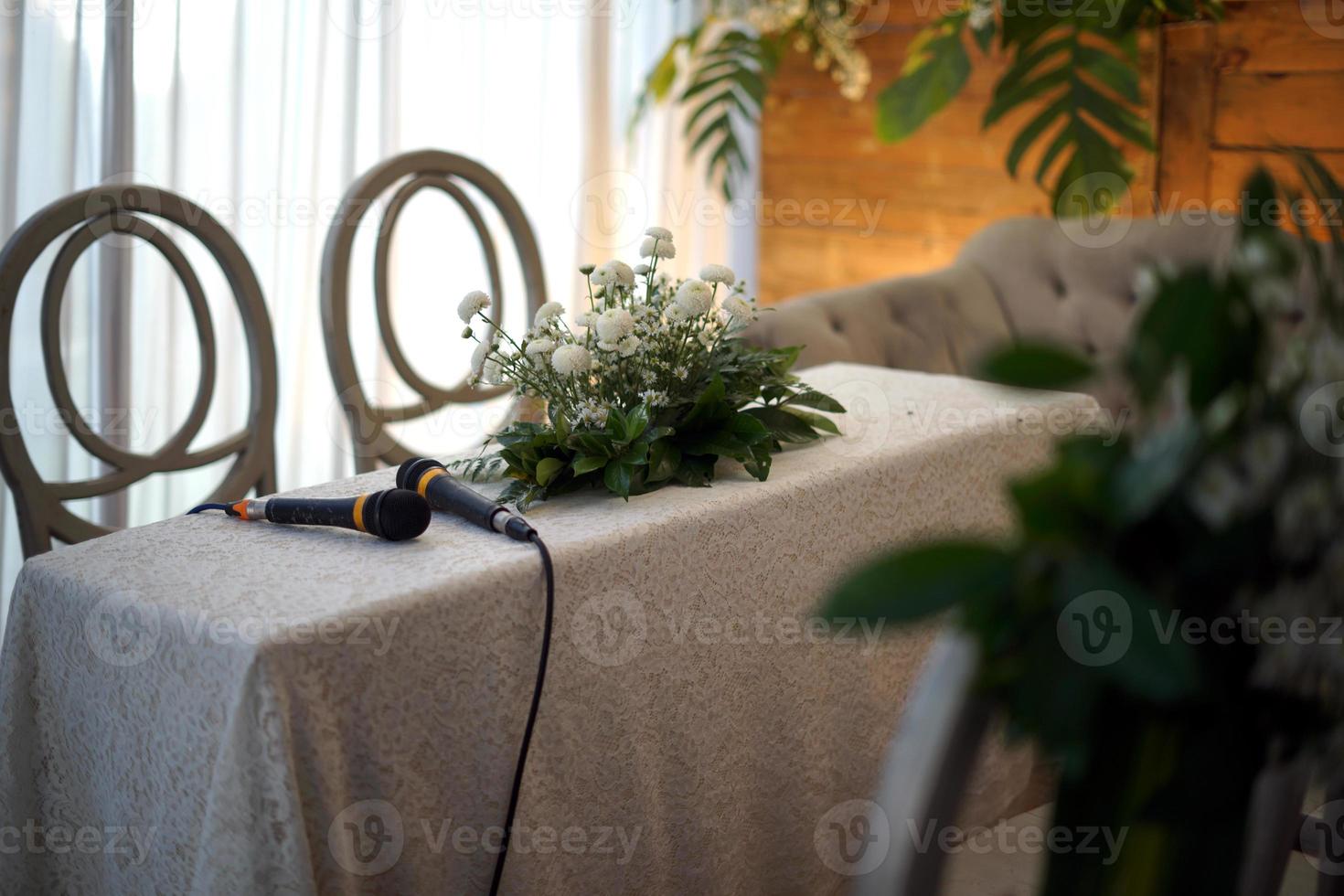 twee microfoons en bloemen Aan een tafel voor bruiloft processie foto