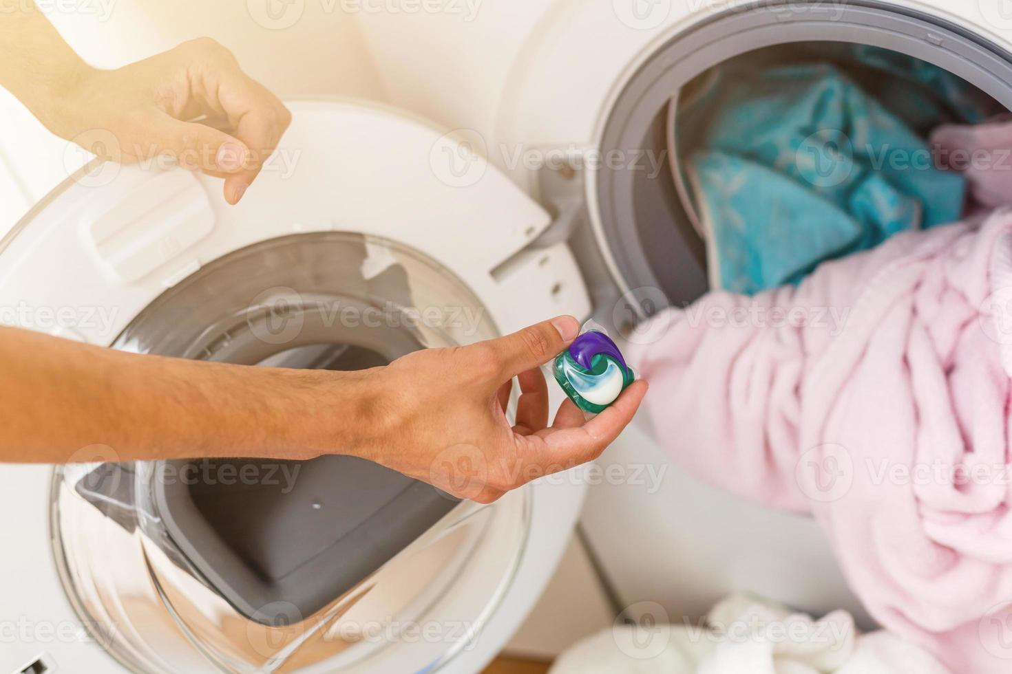 Mens bezig met laden doeken naar het wassen machine. visie van binnen de het wassen machine. foto