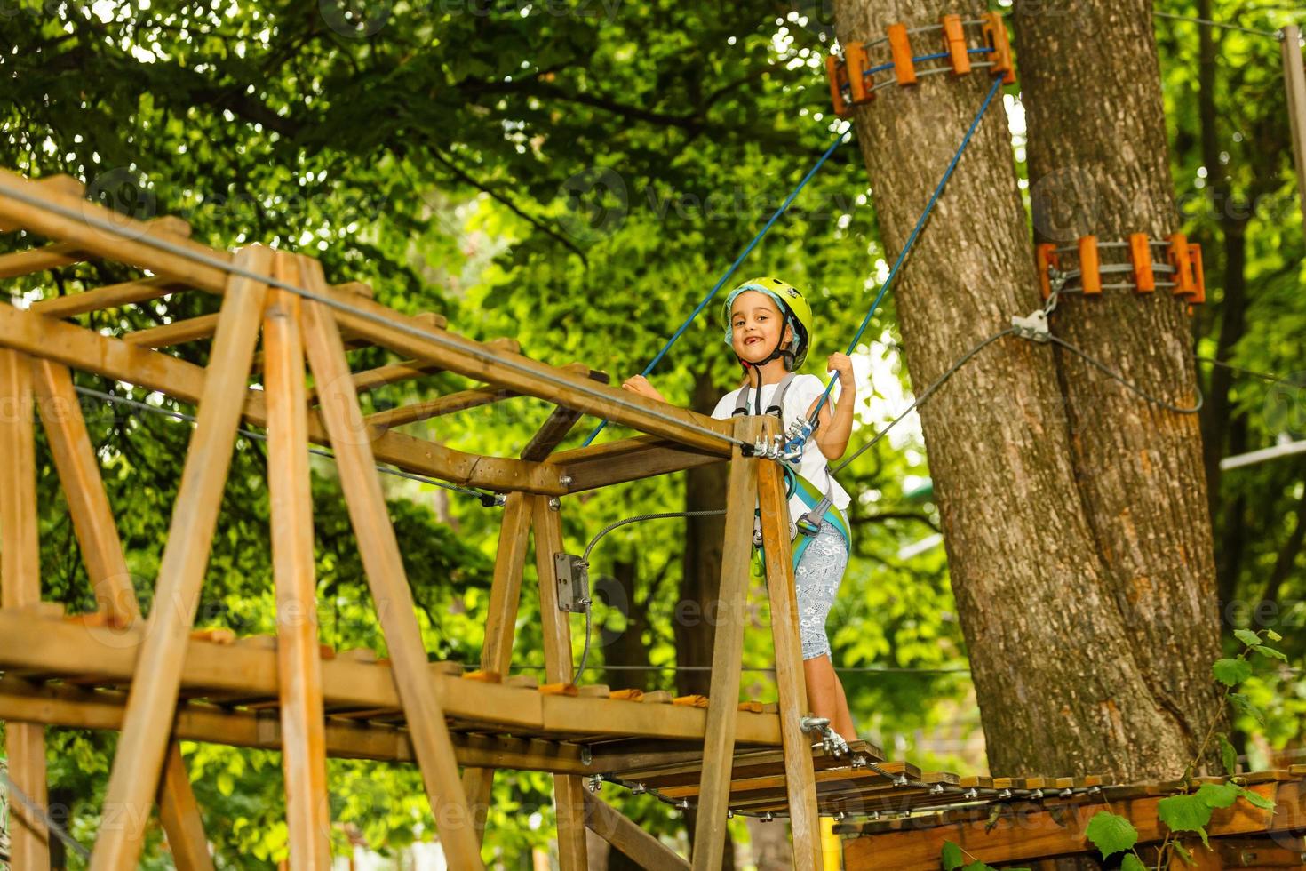 gelukkig schoolmeisje dat van activiteit in een klimavonturenpark geniet op een de zomerdag foto