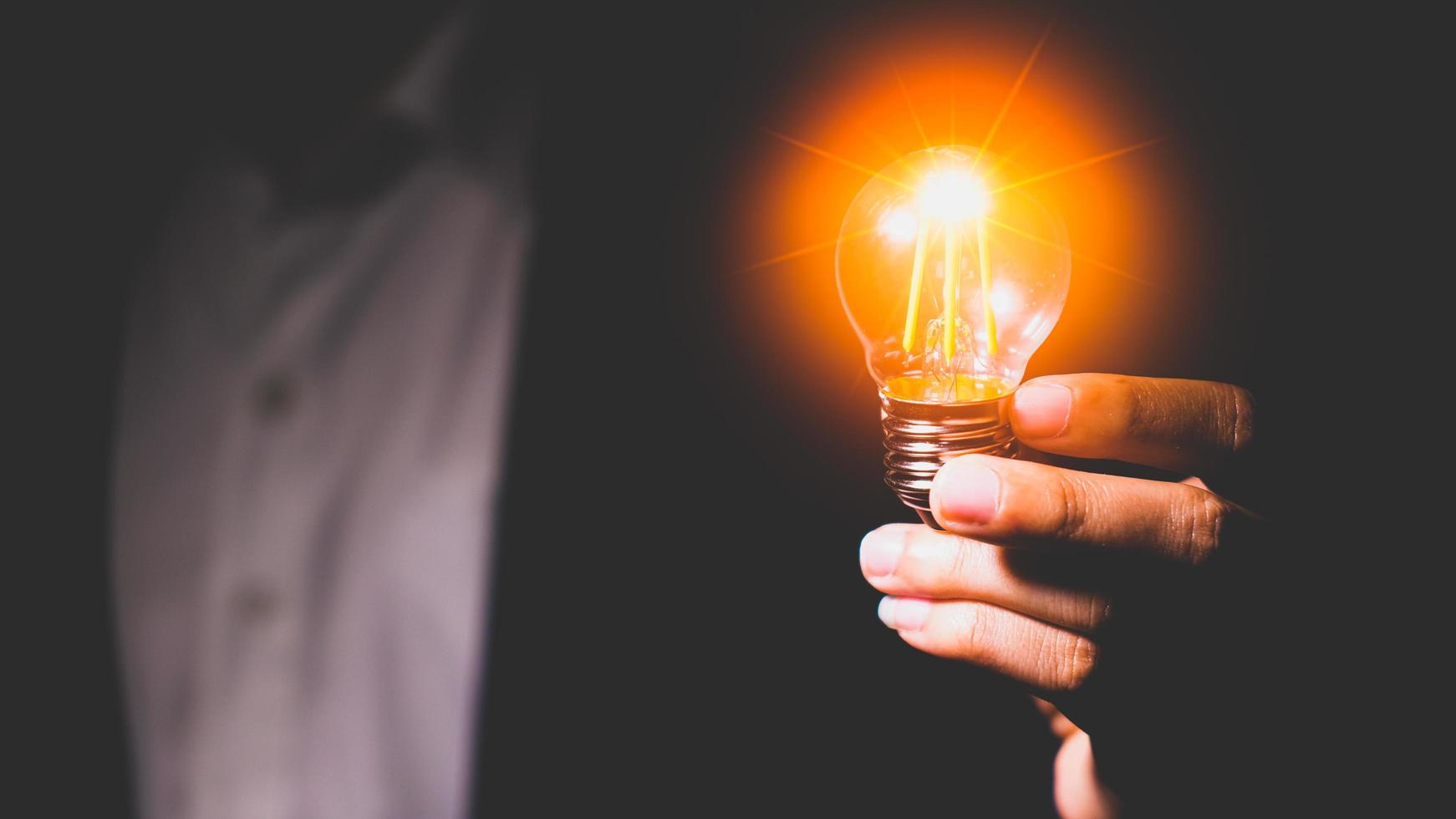 Mens hand- Holding een licht lamp. ideeën, innovaties en inspiratie. creatief idee met sprankelend licht bollen. concept van crisis foto