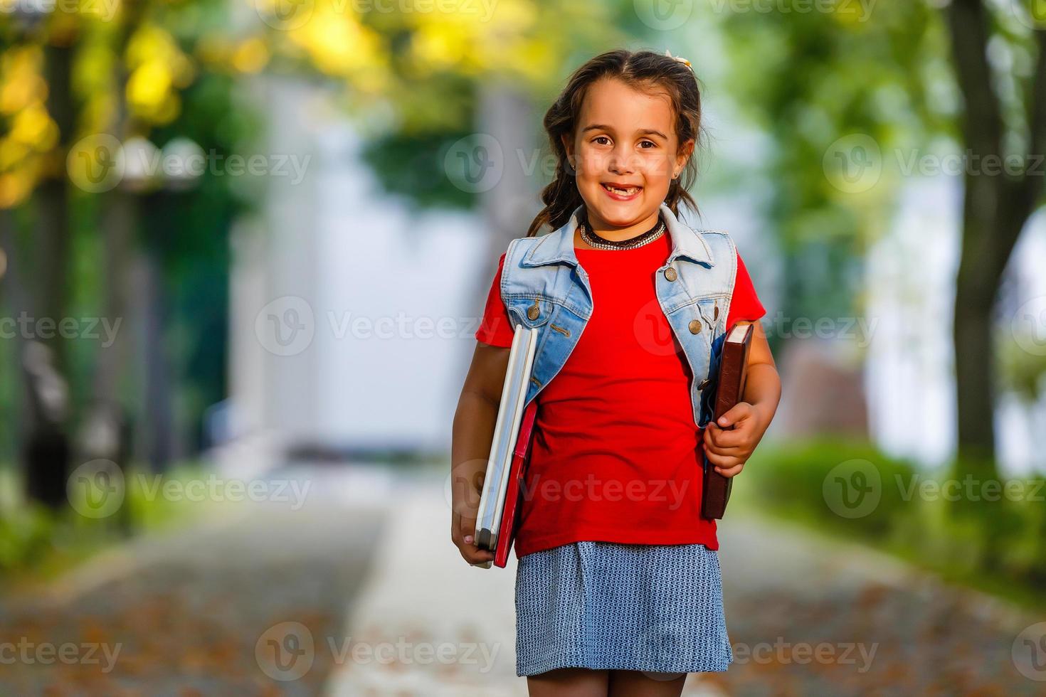 portret van aantrekkelijk Kaukasisch weinig leerling meisje met mooi bruin ogen. gelukkig glimlachen kind op zoek Bij camera - detailopname, buitenshuis. foto