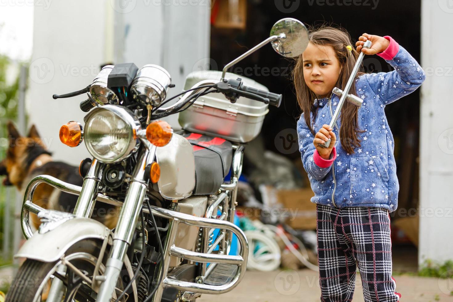weinig meisje repareren een motorfiets, leerling meisje in motor mechanica foto
