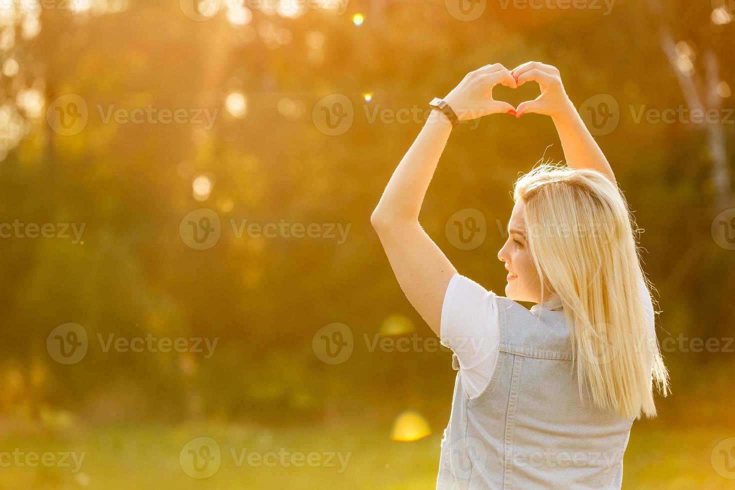 vrouw in natuur Holding hart vorm symbool gemaakt met handen. foto