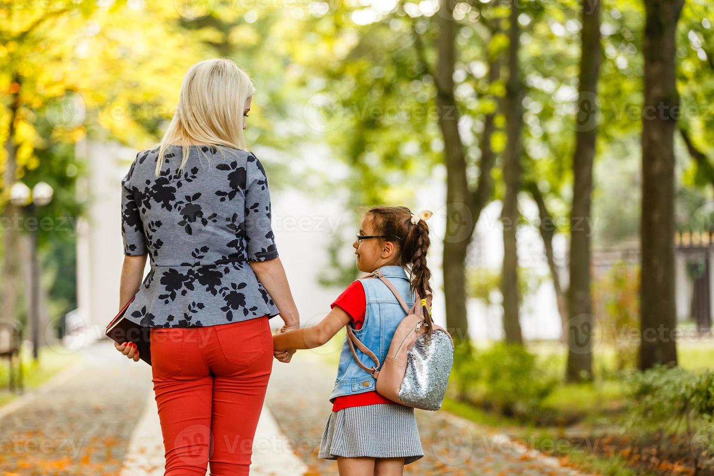 kind gaan terug naar school. begin van nieuw school- jaar na zomer vakantie. weinig meisje met rugzak en boeken Aan eerste school- dag. begin van klas. onderwijs voor kleuterschool en peuter- kinderen. foto