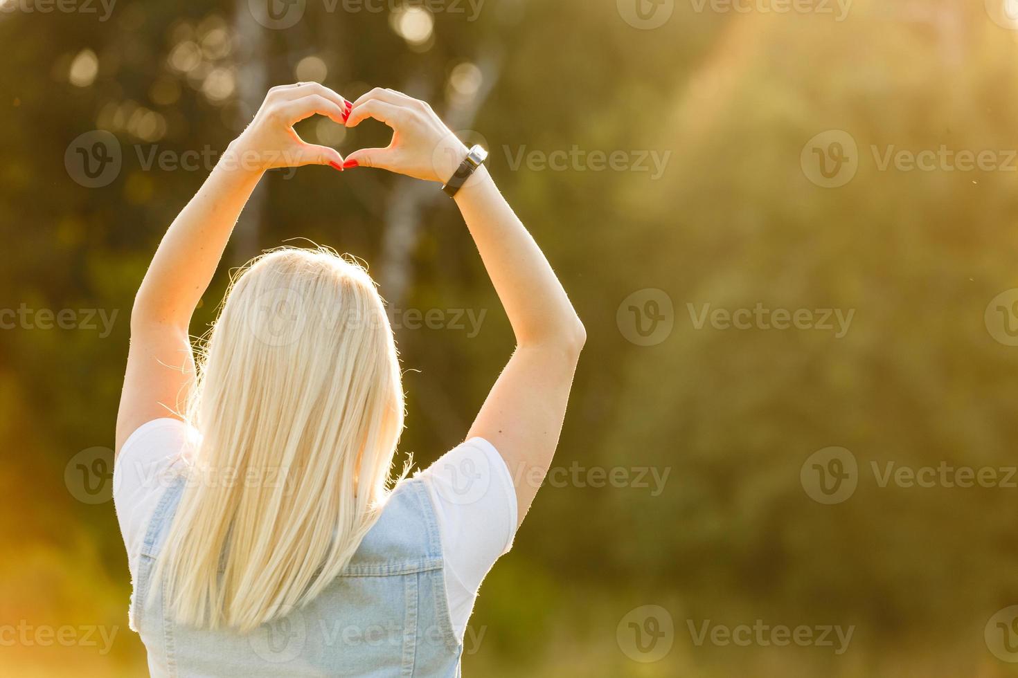 vrouw in natuur Holding hart vorm symbool gemaakt met handen. foto