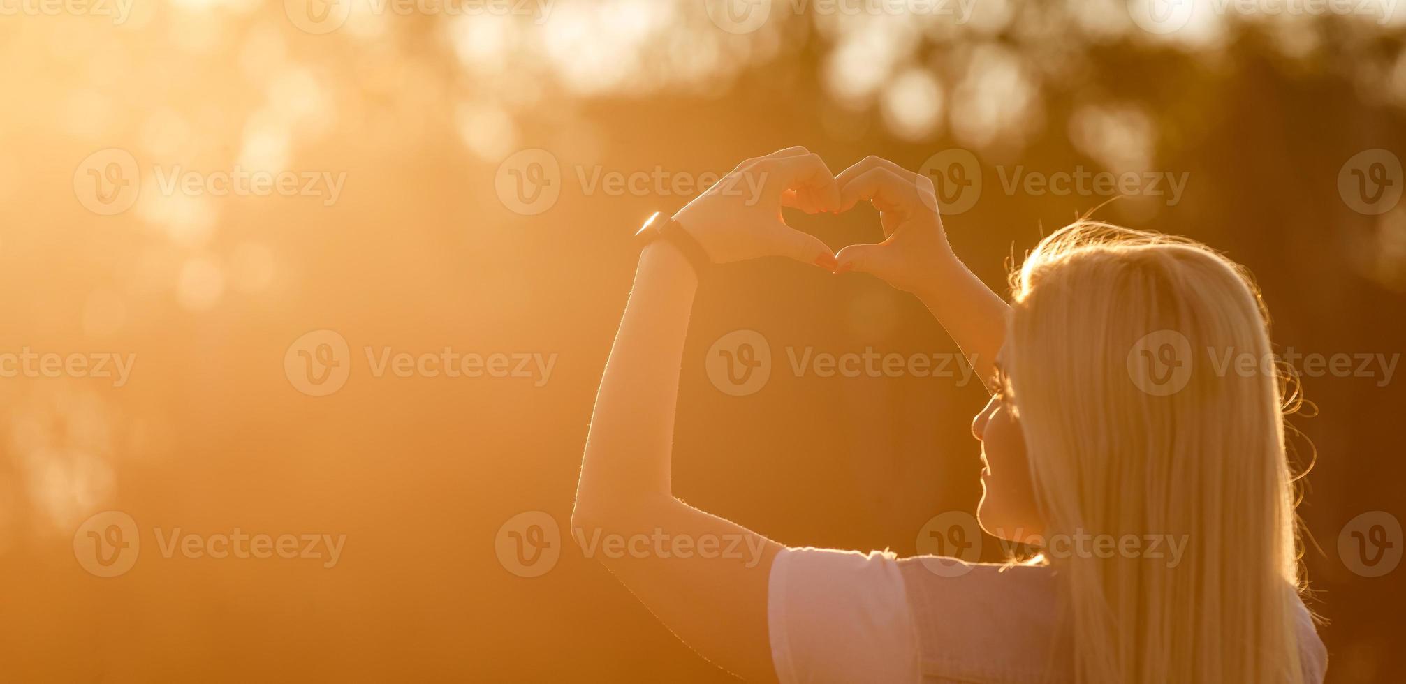 vrouw in natuur Holding hart vorm symbool gemaakt met handen. foto