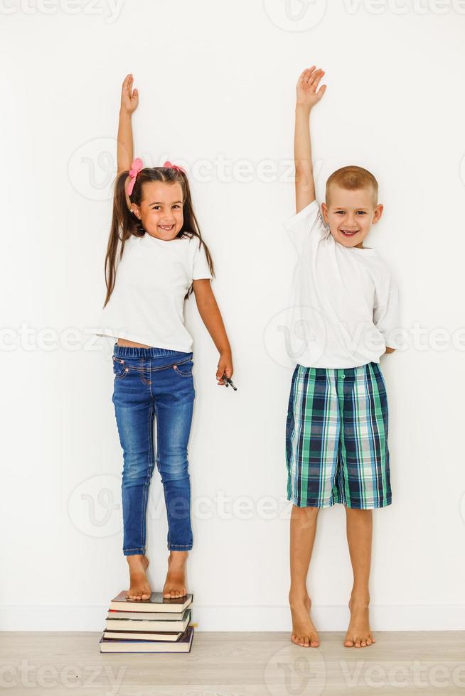 weinig jongen en meisje meten hun hoogte geïsoleerd Aan wit achtergrond foto