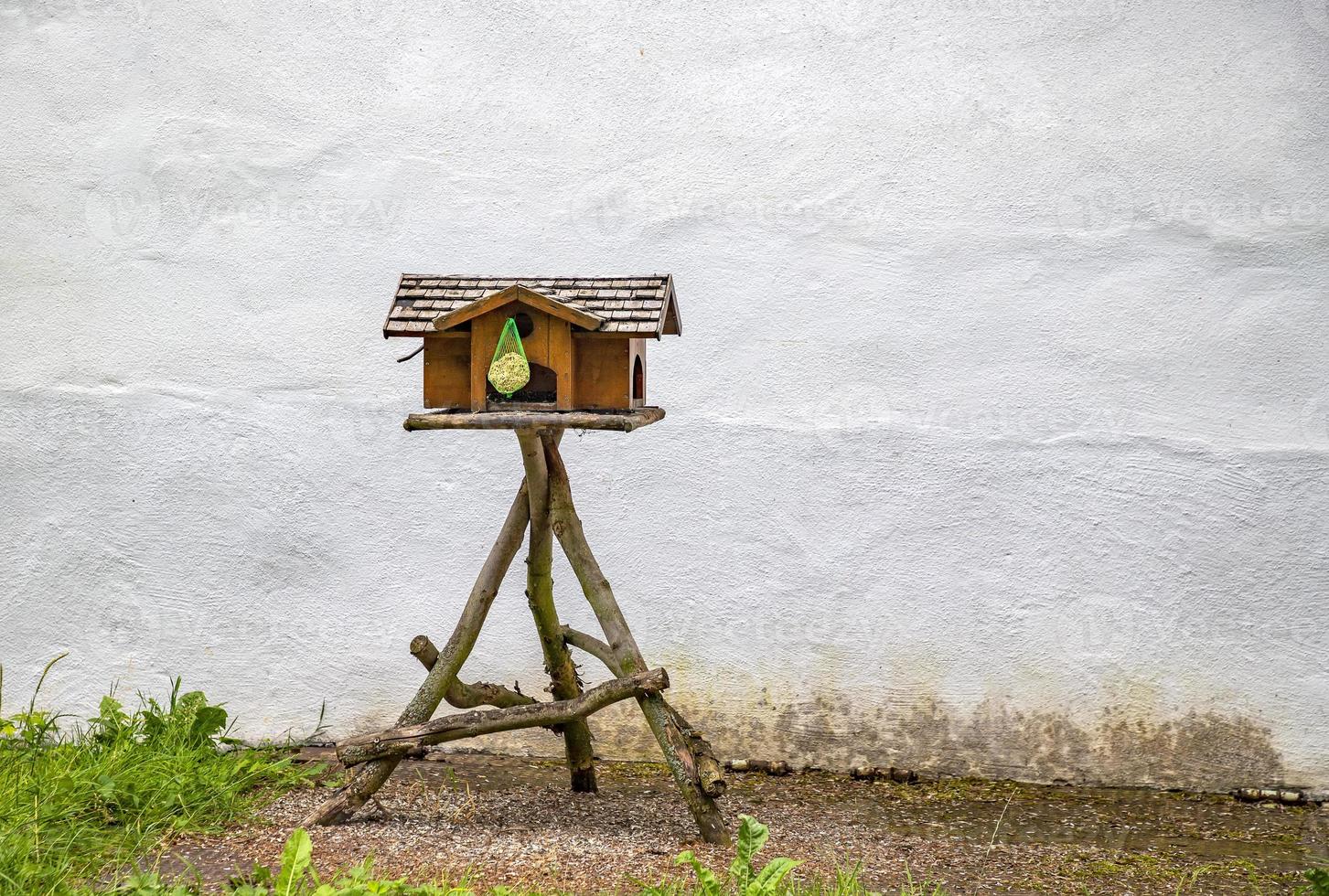 houten klein huis en vogel voeder Bij de tuin. leeg vogelhuisje handgemaakt van hout buitenshuis foto