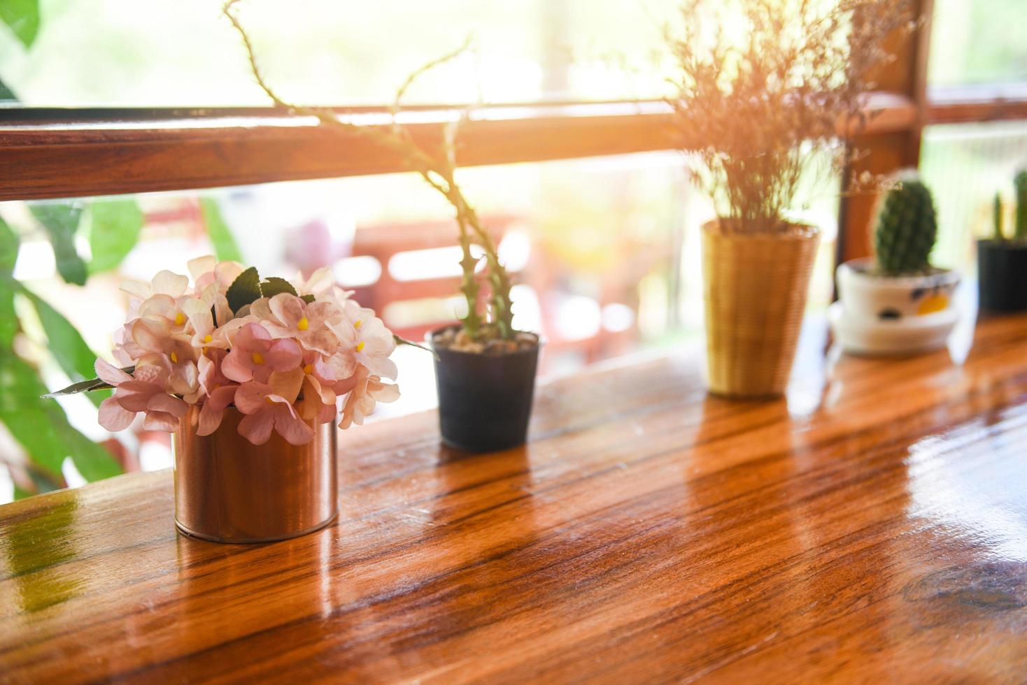 minimaal tafel , fabriek in pot Aan venster met zonlicht - groen huis kamerplanten en houten tafel foto