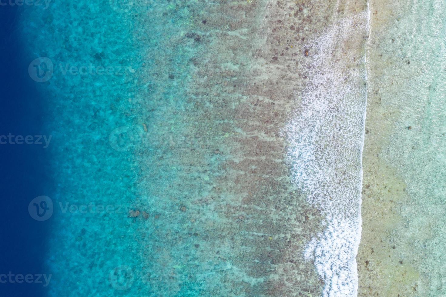 antenne zee visie, top visie van verbazingwekkend natuur oceaan achtergrond. helder blauw water kleuren, lagune strand met golven spatten Bij zonnig dag. vliegend dar foto, verbazingwekkend natuur landschap met koraal rif foto