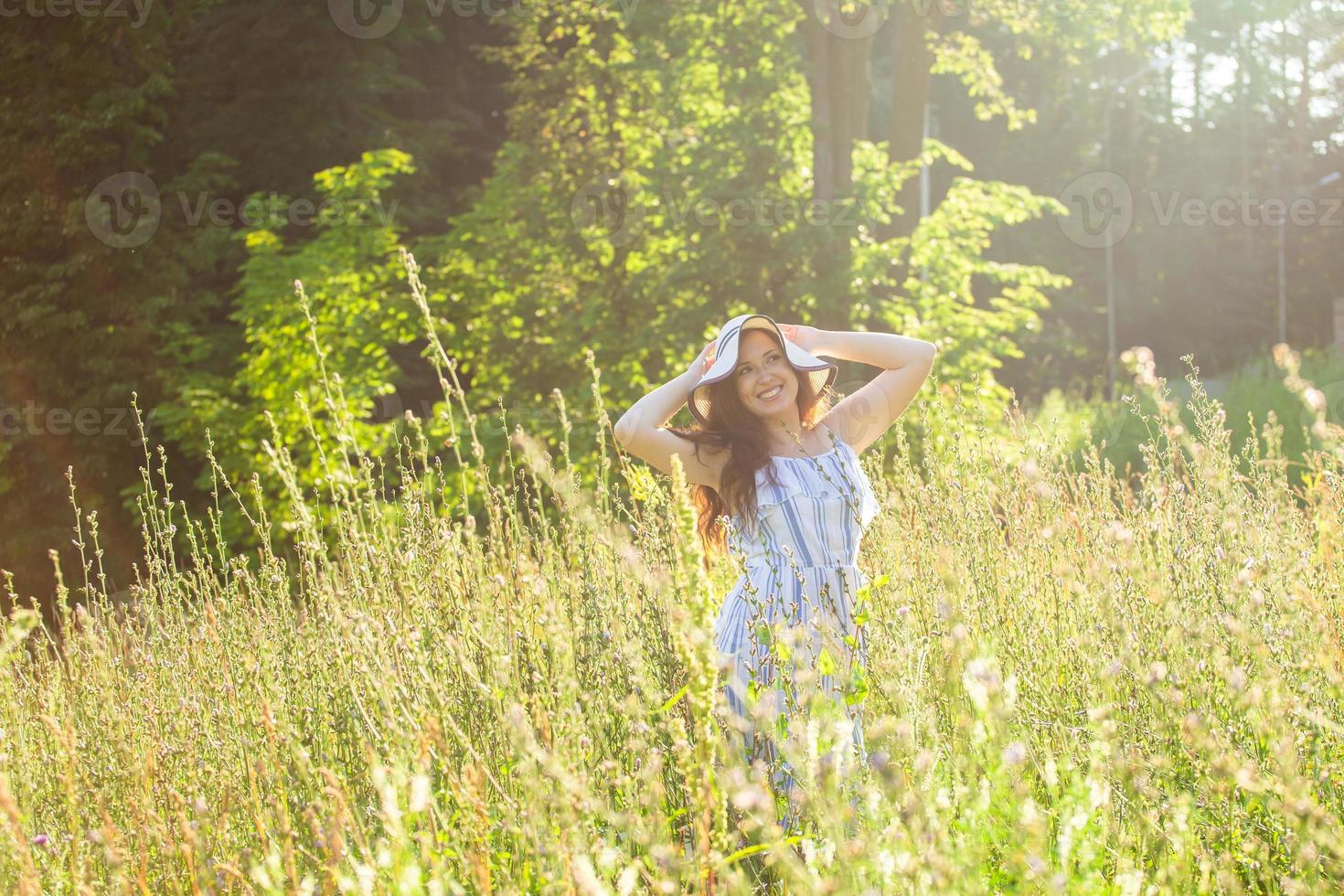 jong vrouw wandelen tussen wilde bloemen Aan zonnig zomer dag. concept van de vreugde van communiceren met zomer natuur foto