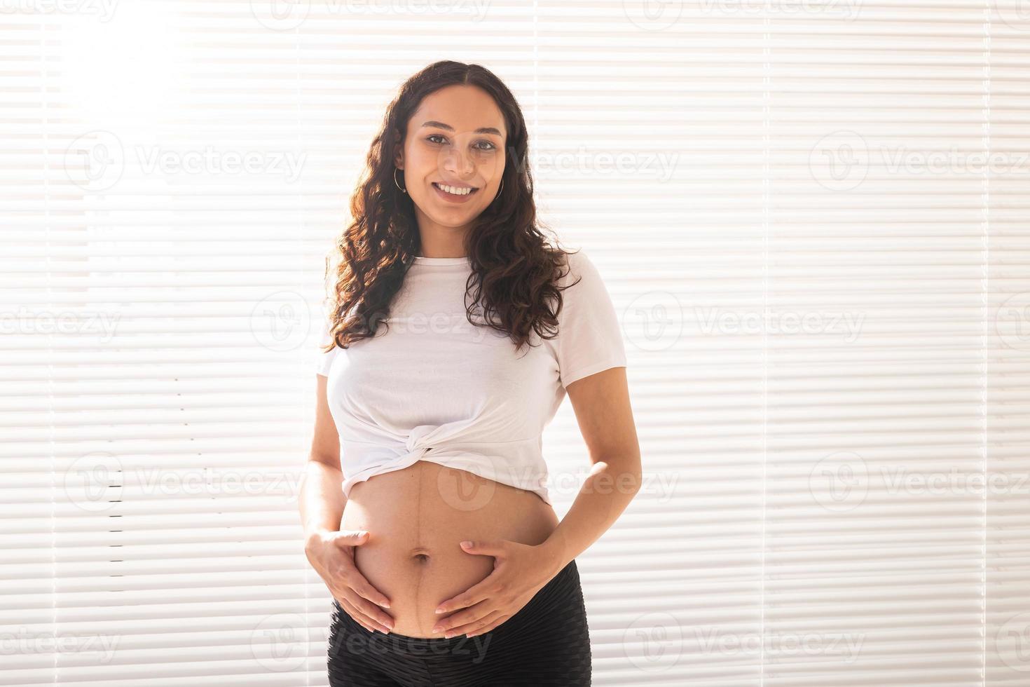 glimlachen jong mooi zwanger vrouw aanraken haar buik en zich verheugen. concept van positief en aangenaam gevoelens terwijl aan het wachten voor de baby. kopiëren ruimte foto