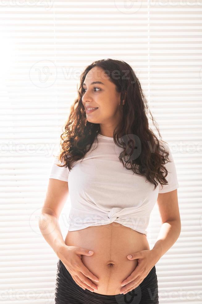 zwanger vrouw aanraken haar buik. zwangerschap en moederschap vertrekken foto