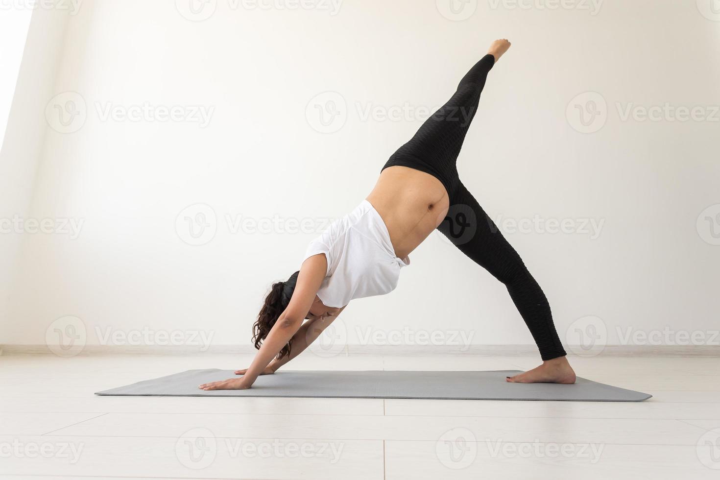 jong flexibel zwanger vrouw aan het doen gymnastiek Aan tapijt Aan de verdieping Aan wit achtergrond. de concept van voorbereidingen treffen de lichaam voor gemakkelijk bevalling foto