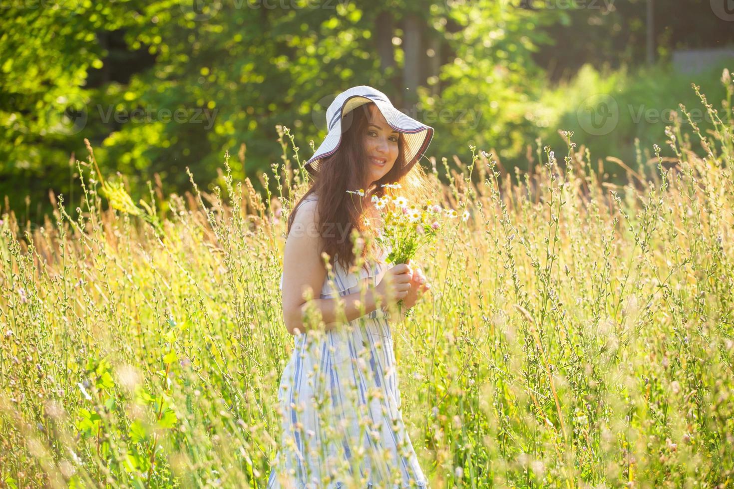 jong vrouw wandelen tussen wilde bloemen Aan zonnig zomer dag. concept van de vreugde van communiceren met zomer natuur foto