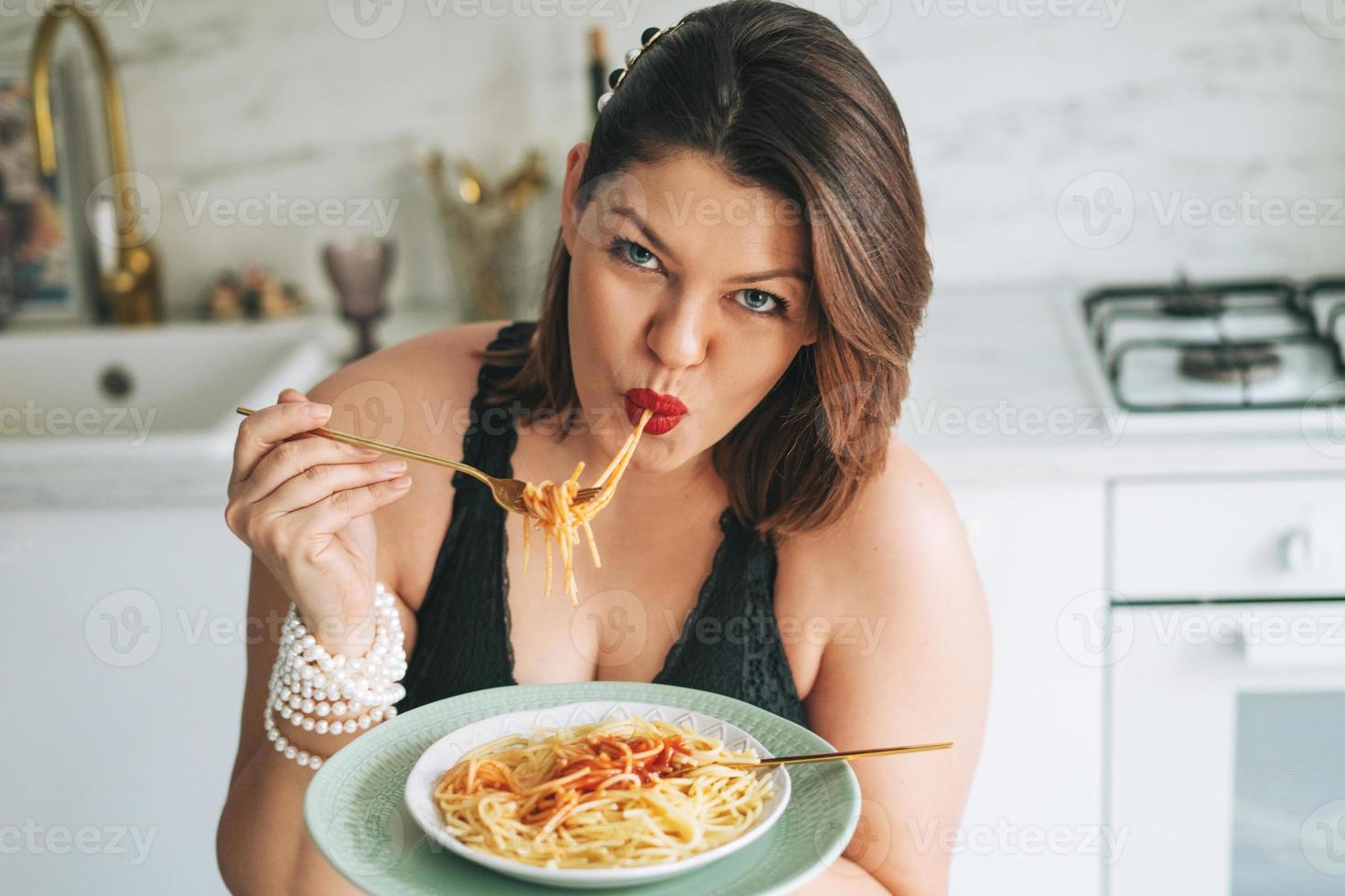 mooi gelukkig sensueel brunette jong vrouw plus grootte lichaam positief met schotel van spaghetti genieten van haar leven Bij huis foto