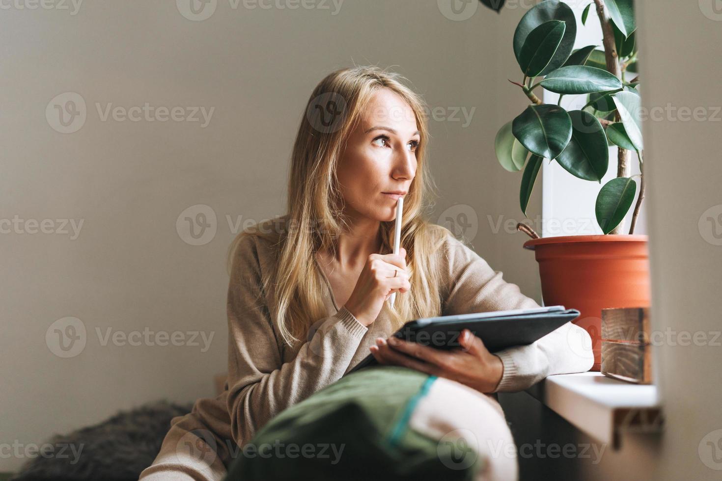 mooi blond jong vrouw artiest illustrator tekening Aan tablet in de buurt venster Bij de huis foto