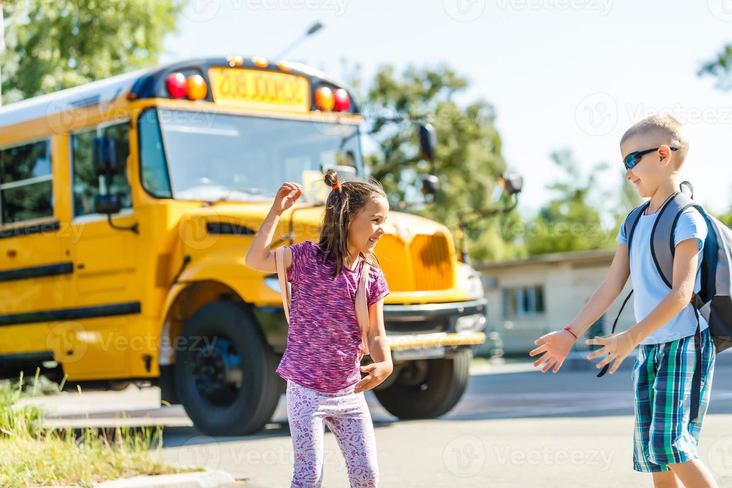mooi weinig schoolmeisje met klasgenoten in de buurt school- bus foto