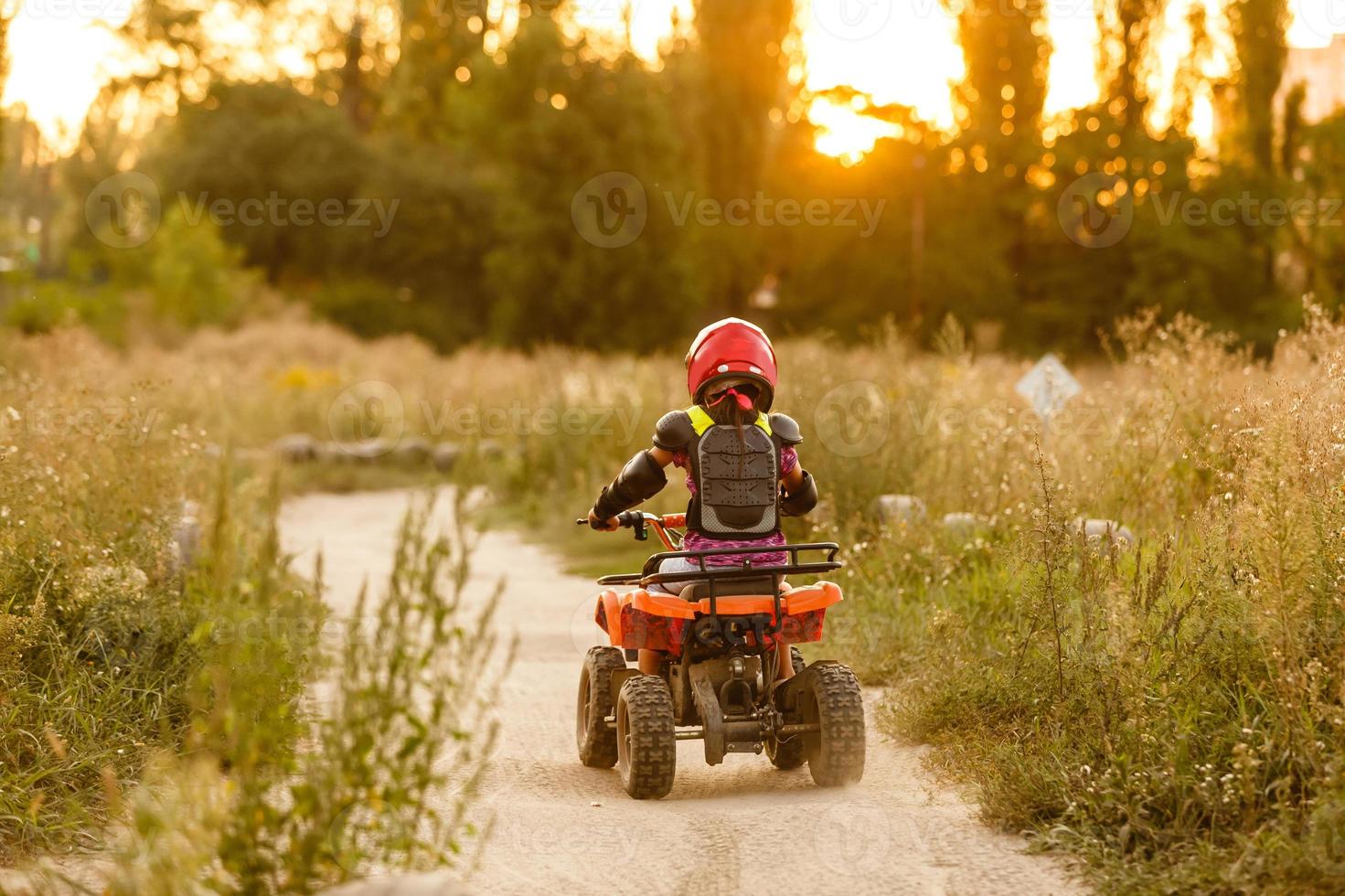 de weinig meisje ritten een quad fiets atv. een mini quad fiets is een koel meisje in een helm en beschermend kleding. elektrisch quad fiets elektrisch auto voor kinderen populariseert groen technologie. foto