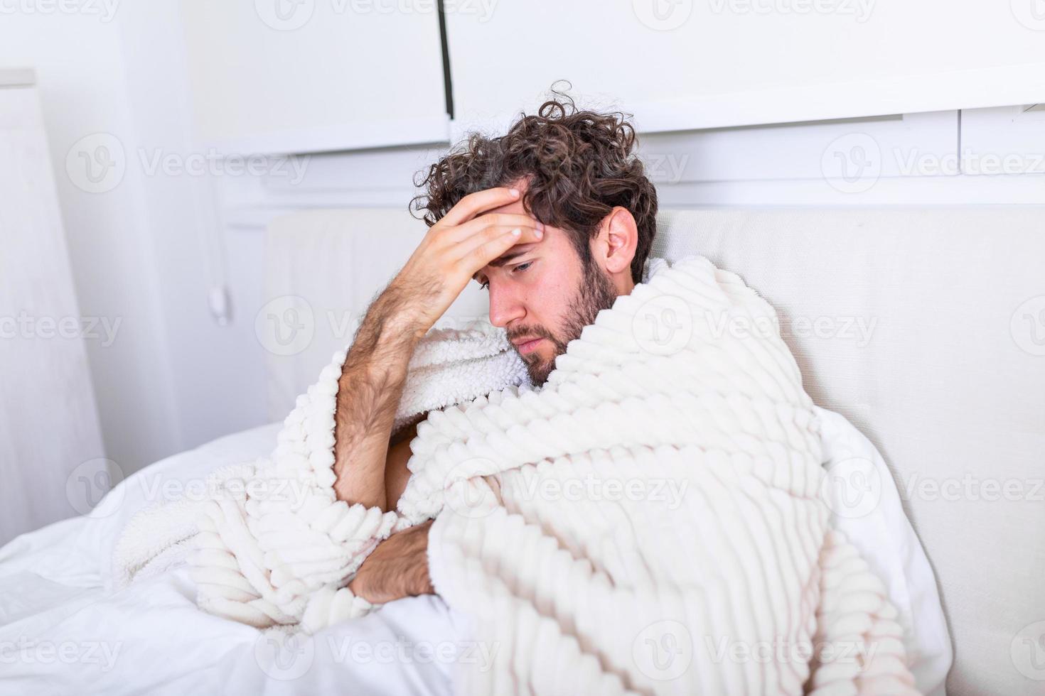 ziek Mens met seizoensgebonden infecties, griep, allergie aan het liegen in bed. ziek knap Mens gedekt met een deken aan het liegen in bed met hoog koorts en een griep, rusten. foto