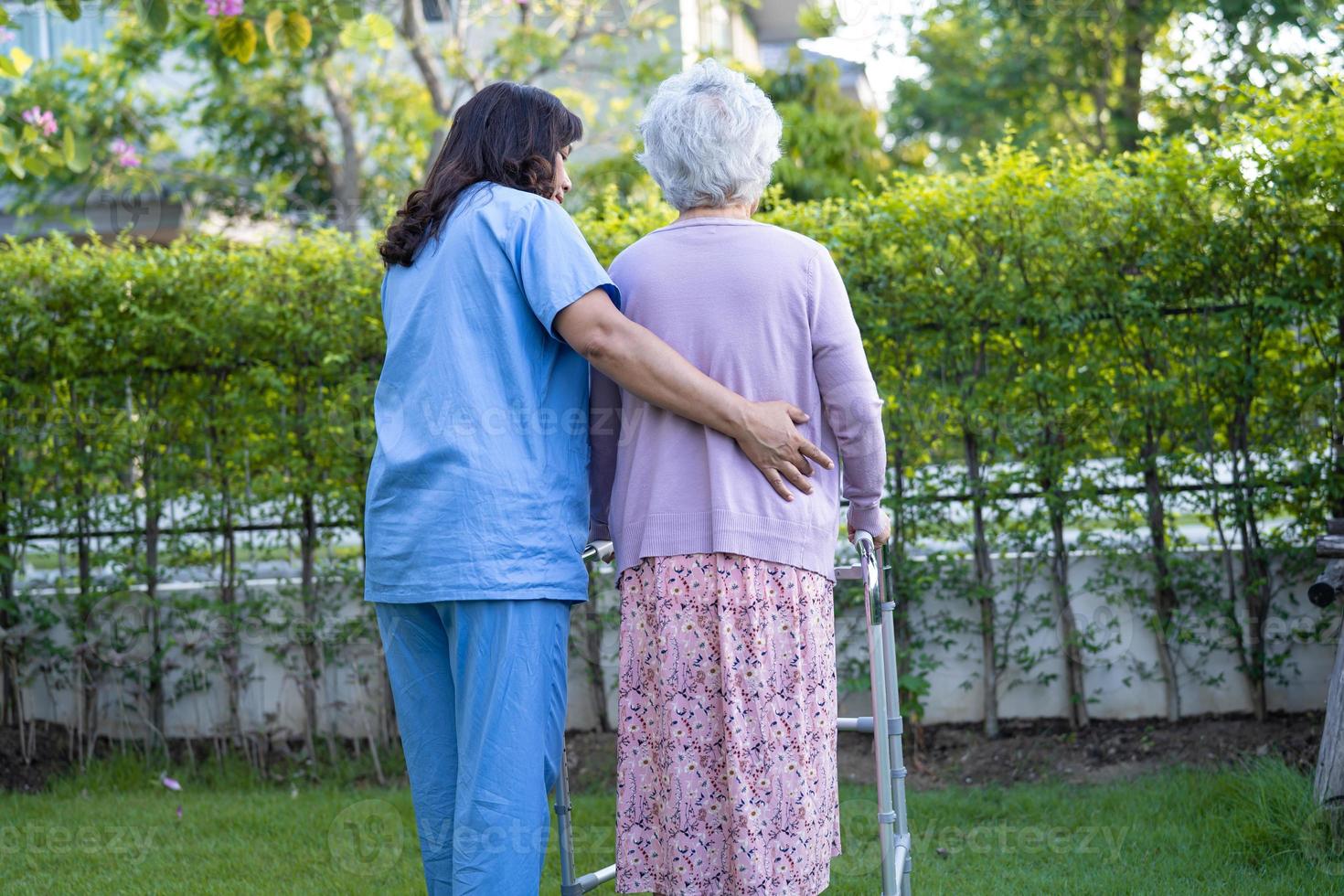 dokter helpt en verzorgt aziatische senior of oudere oude dame vrouw gebruikt rollator met een sterke gezondheid tijdens het wandelen in het park in een fijne frisse vakantie. foto