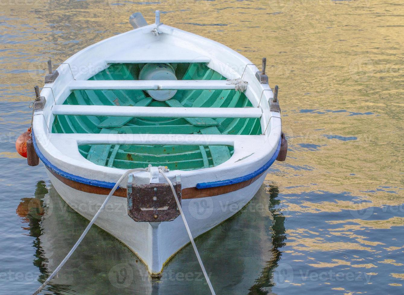 wit afgemeerd boot Aan een rivier- zijn oceaan met touw en reflectie foto