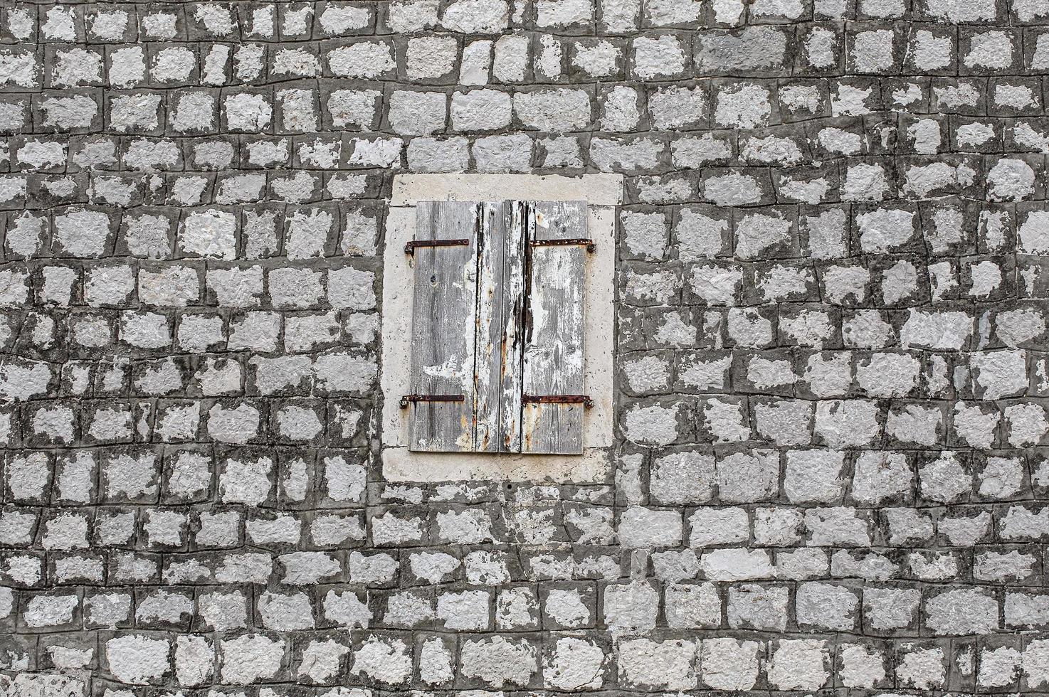 oud huis steen muur, met gebarsten venster luiken in licht hout foto