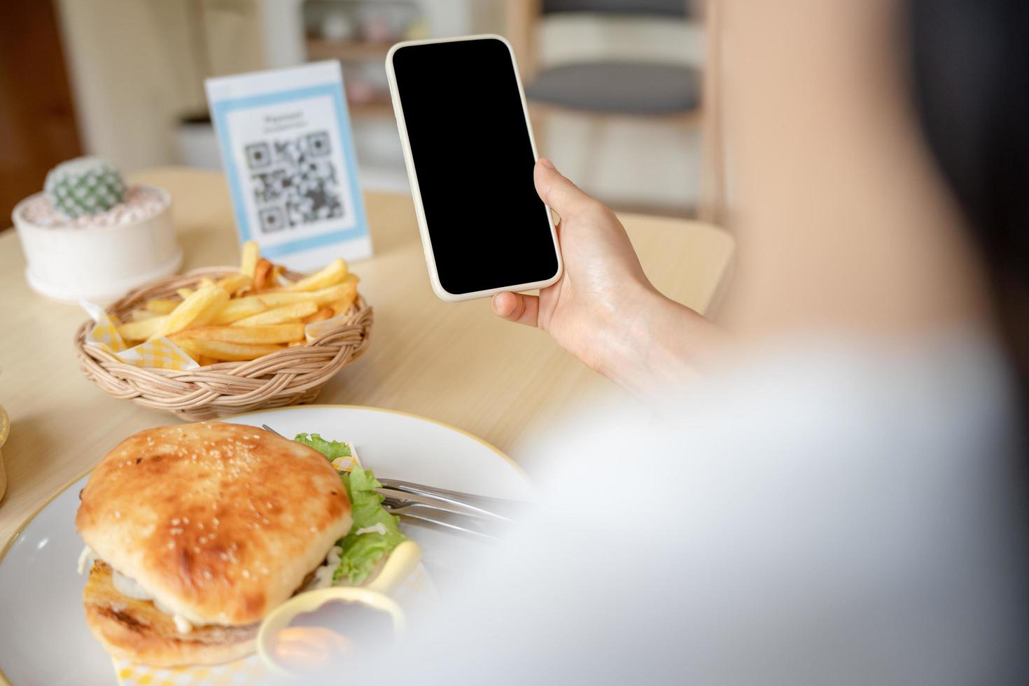 mensen gebruik smartphone naar scannen qr code in cafe. de restaurant gebouwd een digitaal betaling systeem zonder contant geld. qr code betalen, e portemonnee, contant geld technologie, betalen online foto