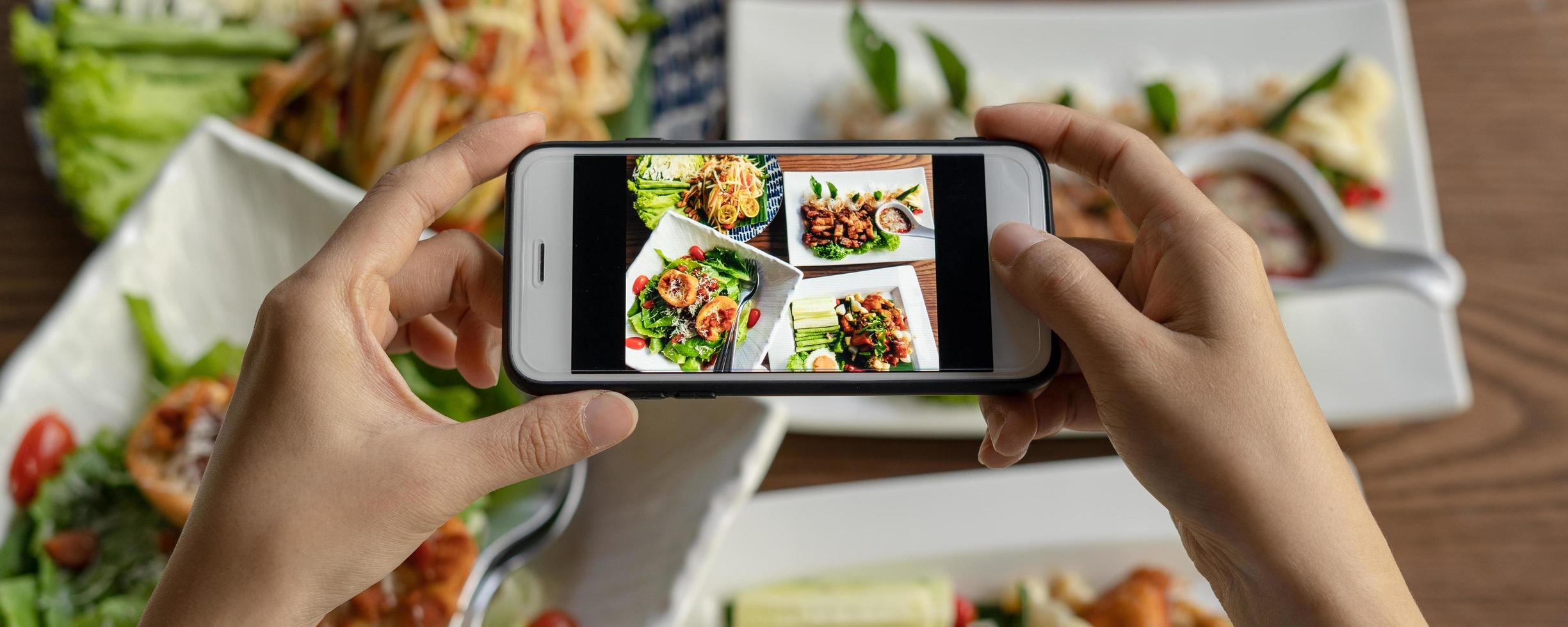 vrouw nemen afbeelding van een maaltijd Aan de tafel na bestellen voedsel online naar eten Bij huis. fotografie en gebruik telefoon concepten foto