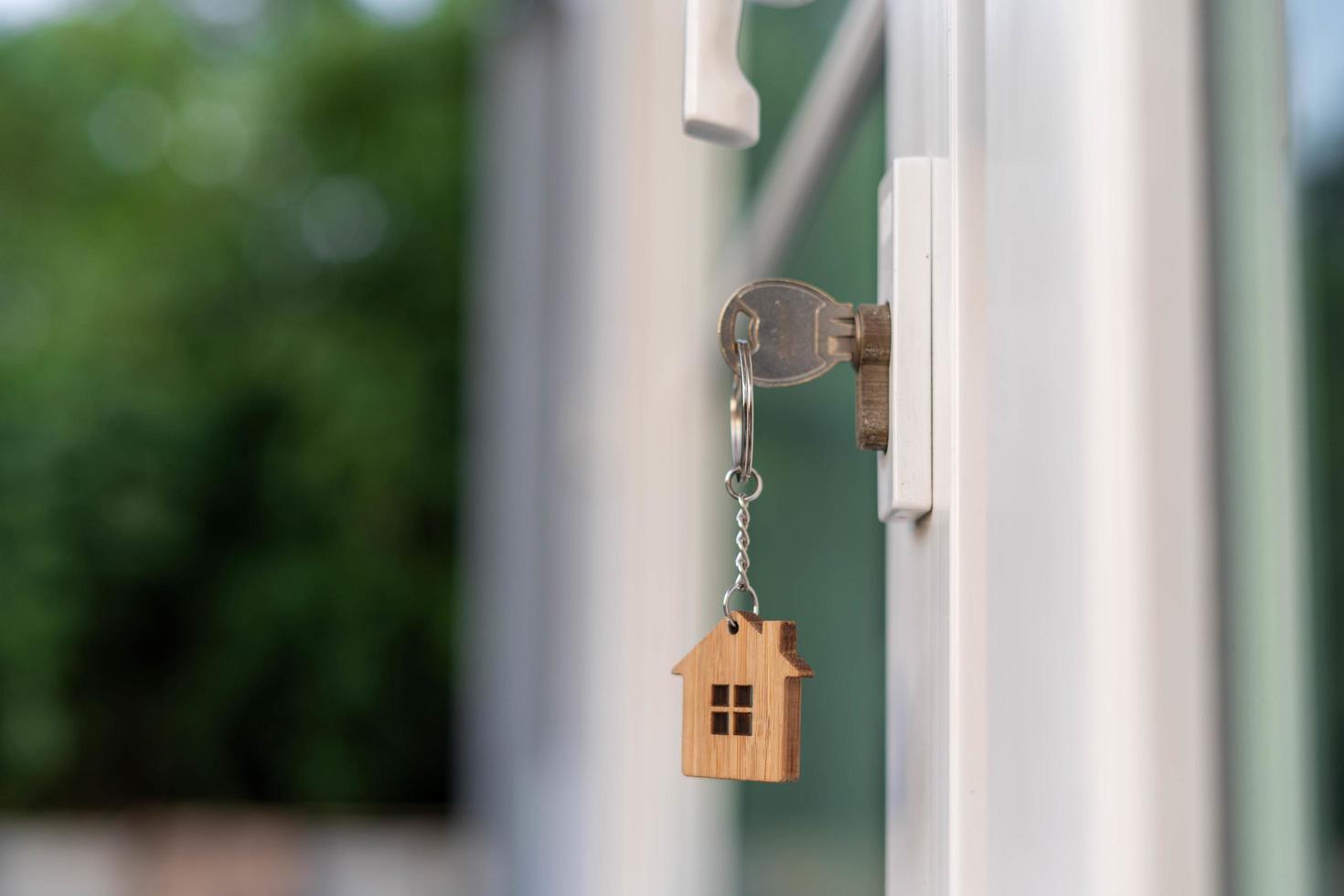 landheer sleutel voor ontgrendelen huis is aangesloten in de deur. tweede hand- huis voor huur en uitverkoop. sleutelhanger is blazen in de wind. hypotheek voor nieuw huis, kopen, verkopen, renoveren, investering, baasje, landgoed foto