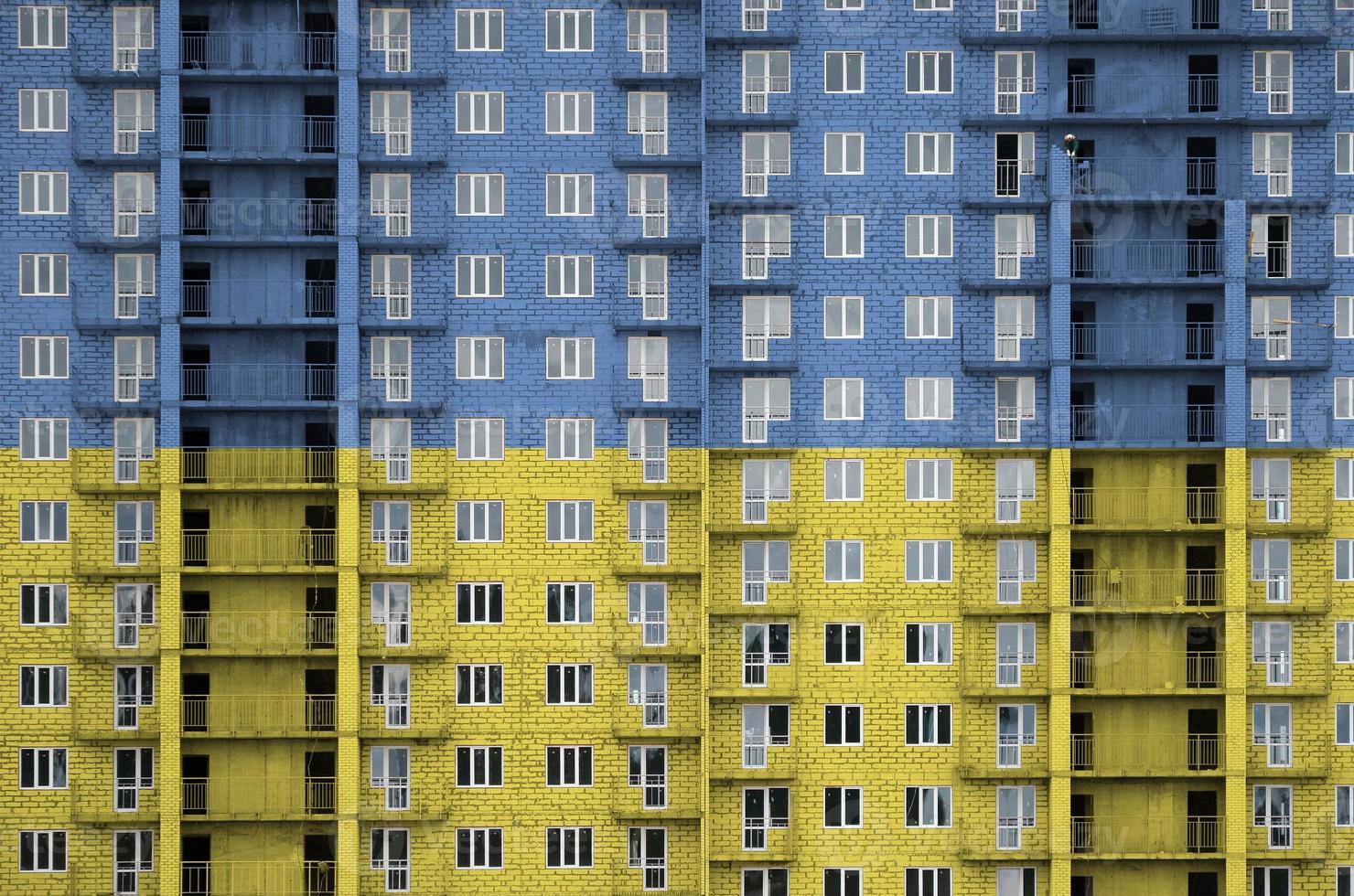 Oekraïne vlag afgebeeld in verf kleuren Aan meerdere verdiepingen woonachtig gebouw onder bouw. getextureerde banier Aan steen muur achtergrond foto