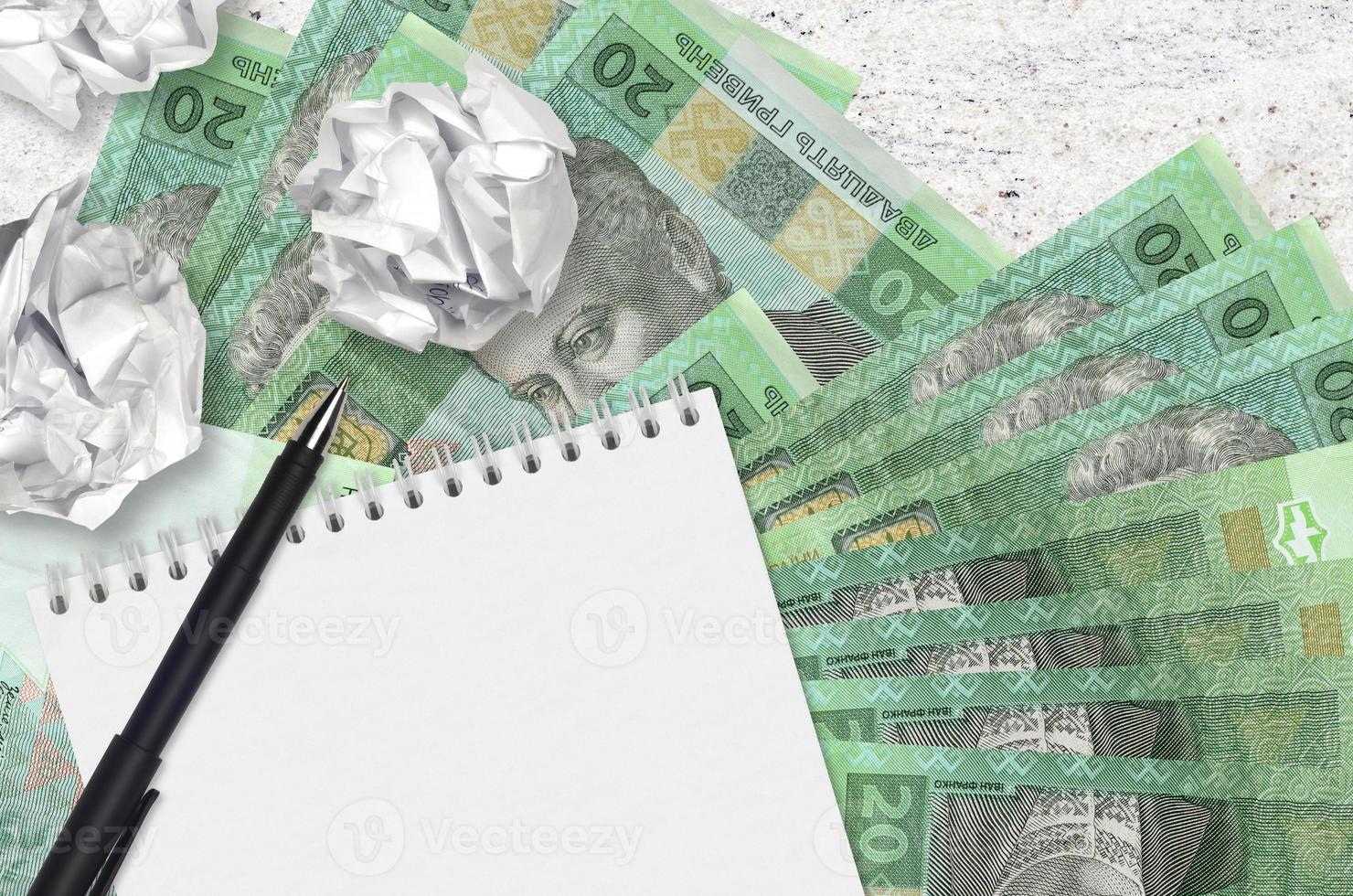 20 oekraïens grivna's rekeningen en ballen van verfrommeld papier met blanco kladblok. slecht ideeën of minder van inspiratie concept. zoeken ideeën voor investering foto