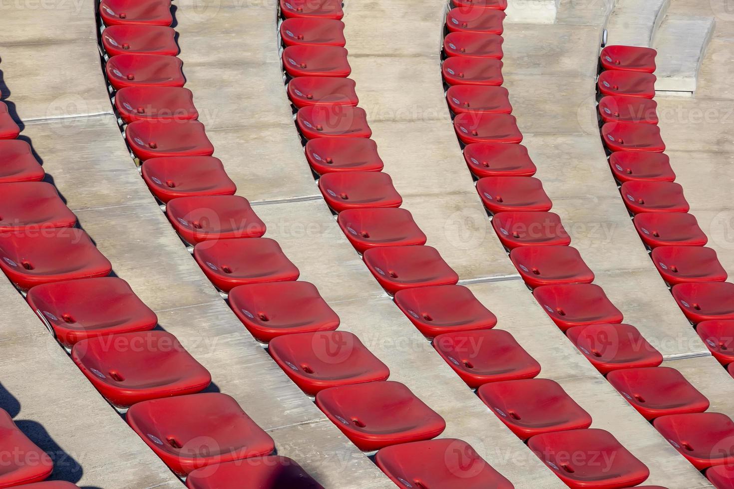rijen van leeg plastic rood stoelen in de buitenshuis theater Aan een zonnig dag. foto