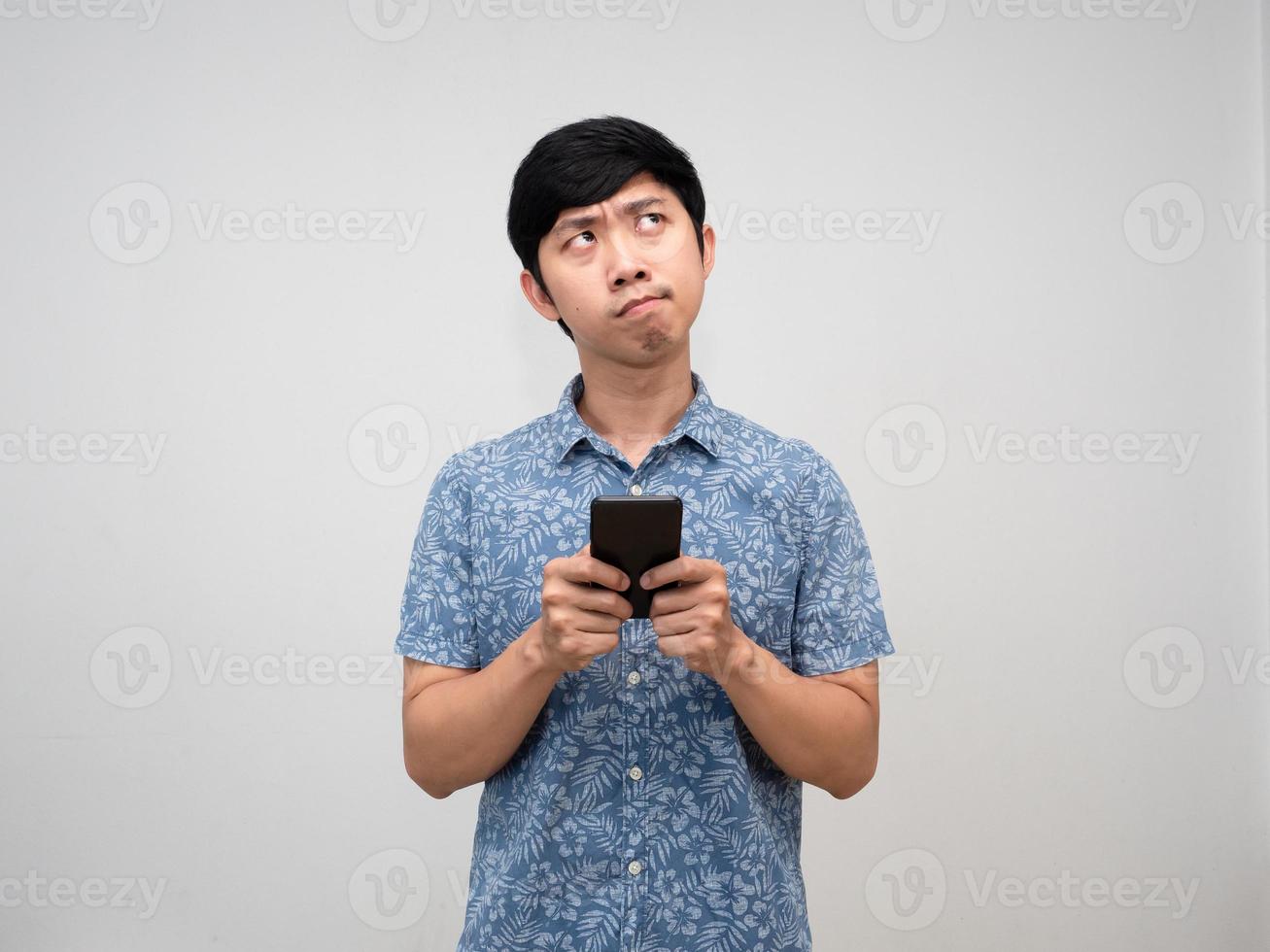 Aziatisch Mens blauw overhemd Holding mobiel telefoon gebaar denken iets en voelt verward geïsoleerd foto
