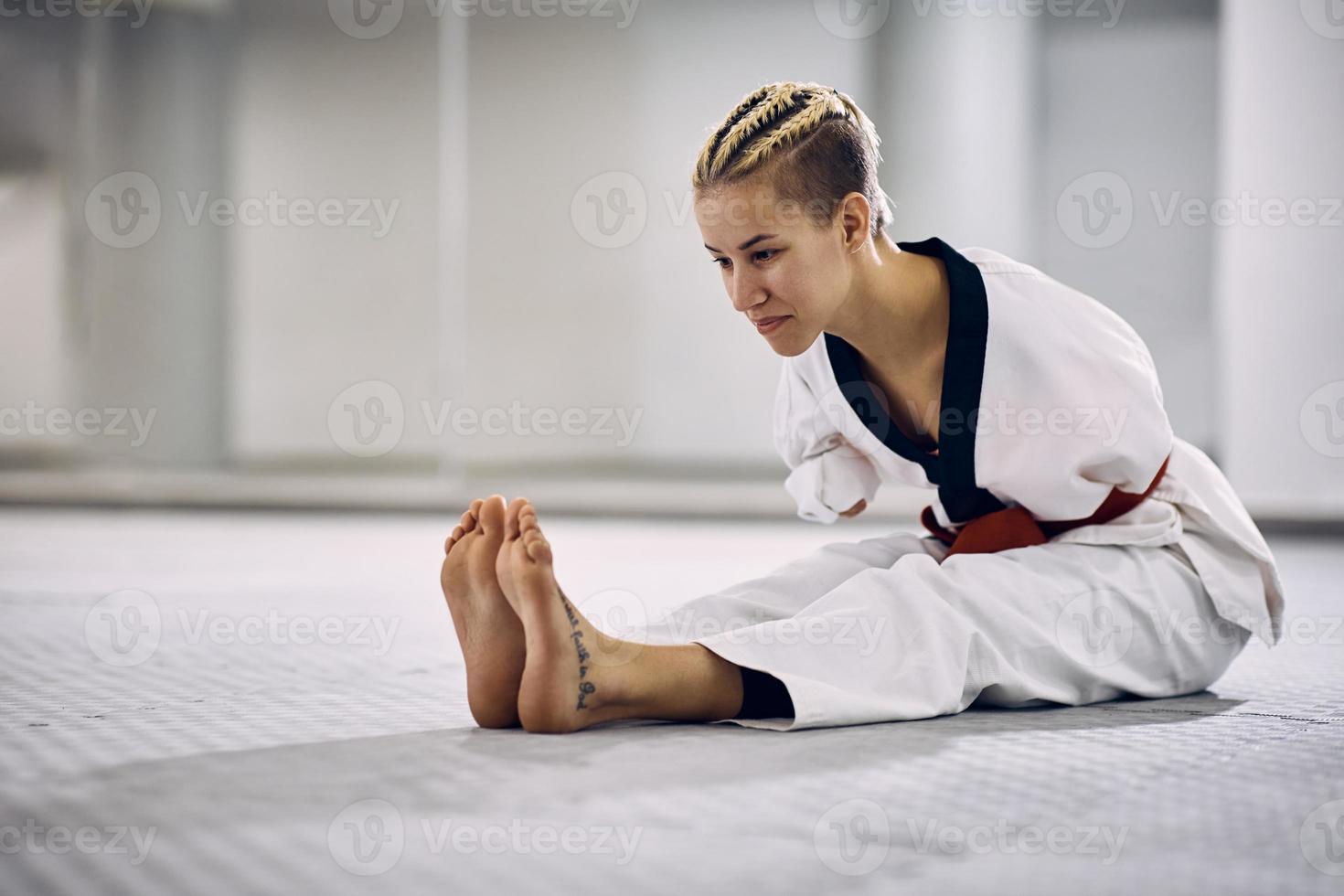 jong atletisch vrouw met para-vermogen uitrekken Aan de verdieping gedurende taekwondo opleiding in Gezondheid club foto