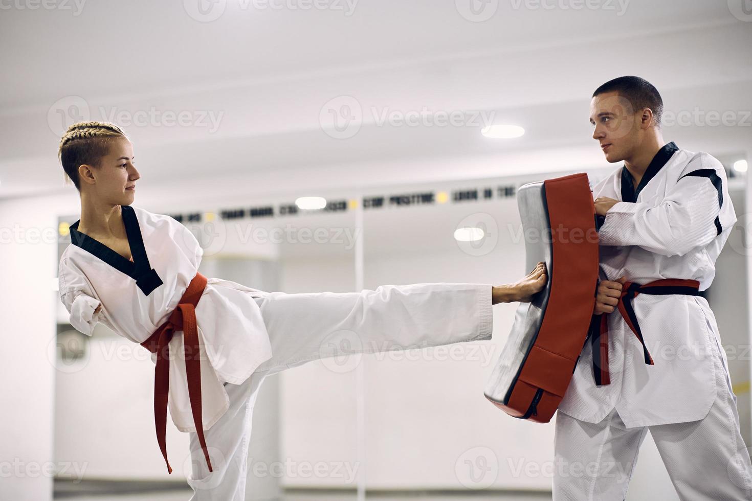 vrouw krijgshaftig artiest met onbekwaamheid oefenen been trap met haar instructeur gedurende taekwondo opleiding in Gezondheid club. foto