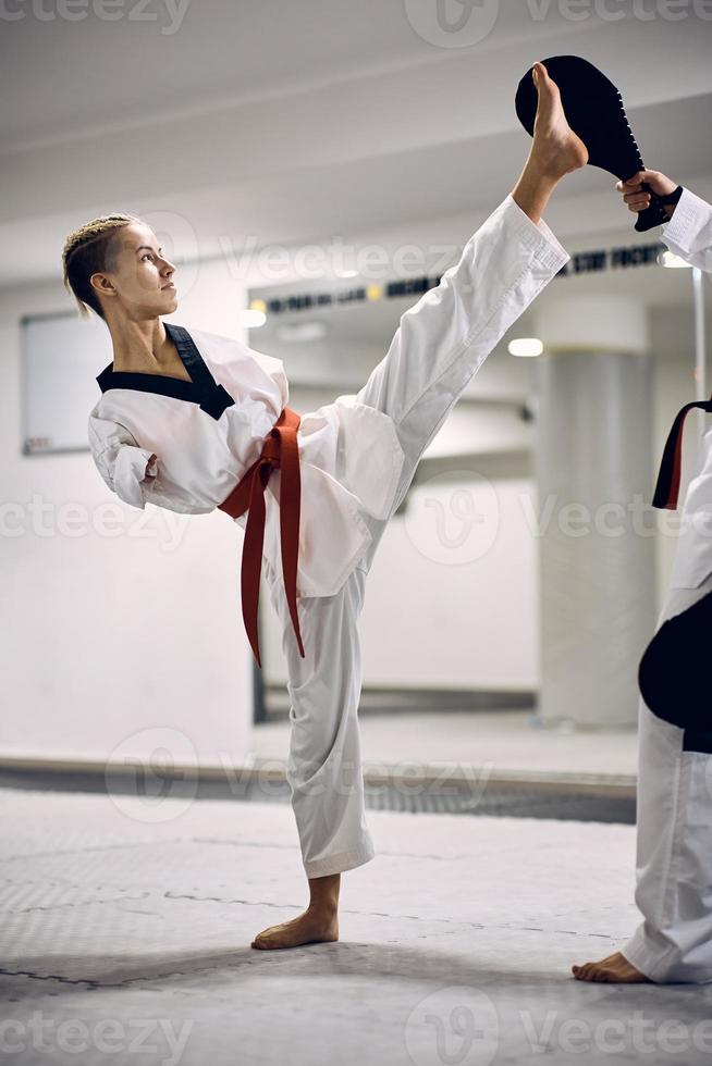 krijgshaftig artiest met para-vermogen oefenen hoog trap met haar spaarzaam partner gedurende taekwondo opleiding in Gezondheid club. foto