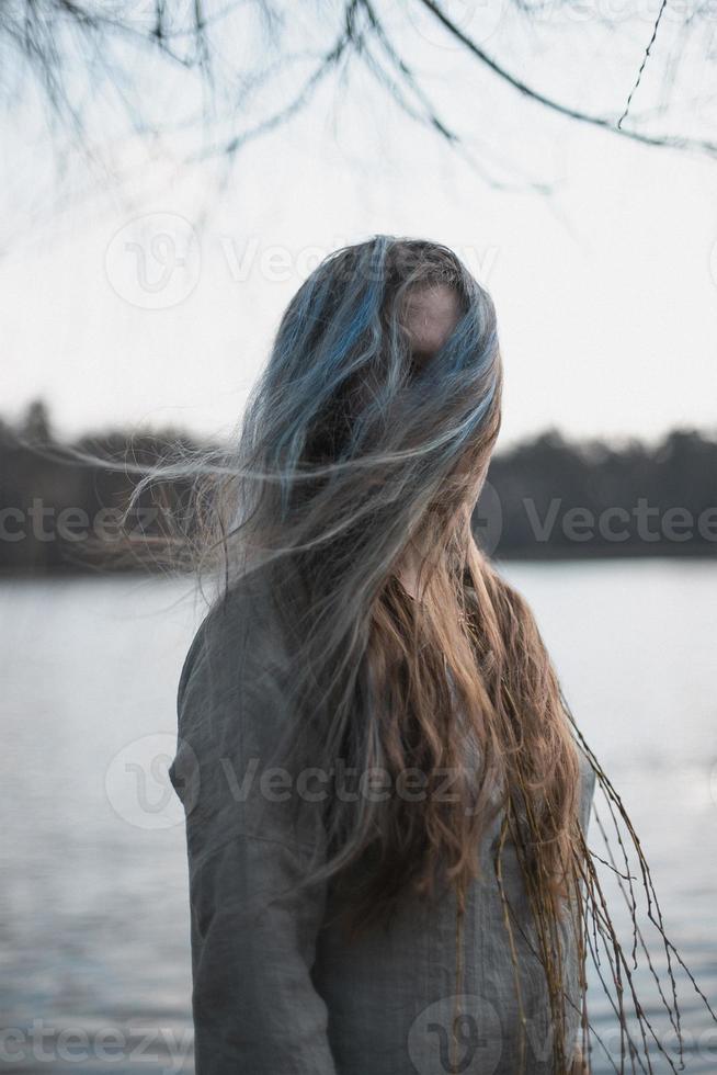 dichtbij omhoog haar- vloeiende in wind en aan het bedekken volwassen vrouw gezicht portret afbeelding foto