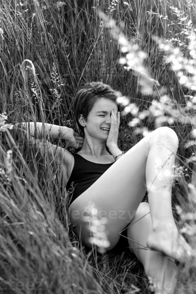 lachend vrouw aan het liegen Aan gras monochroom toneel- fotografie foto