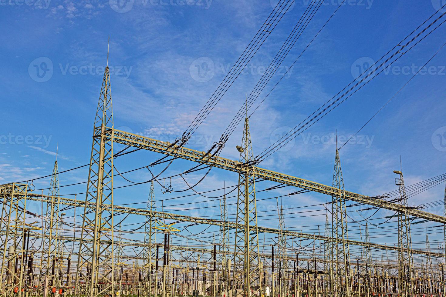 afbeelding van een transformator station met veel isolatoren en kabels gedurende de dag foto