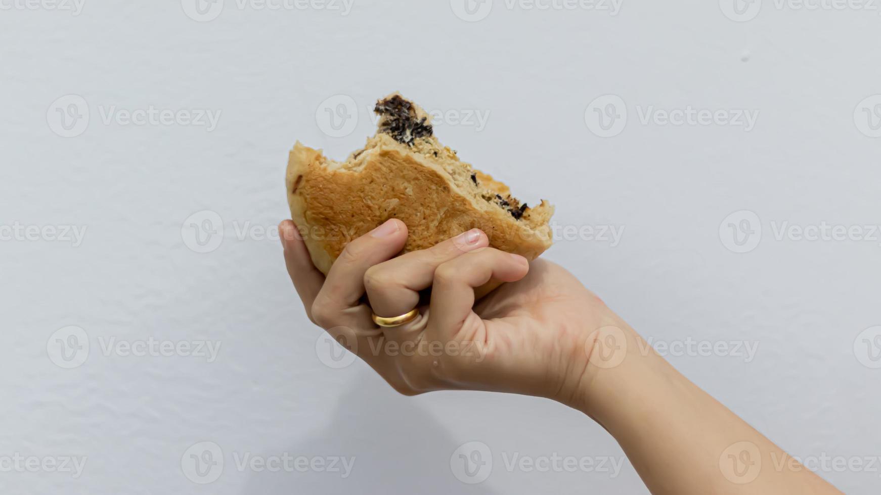 vrouw hand- Holding een chocola donut tegen een wit achtergrond foto