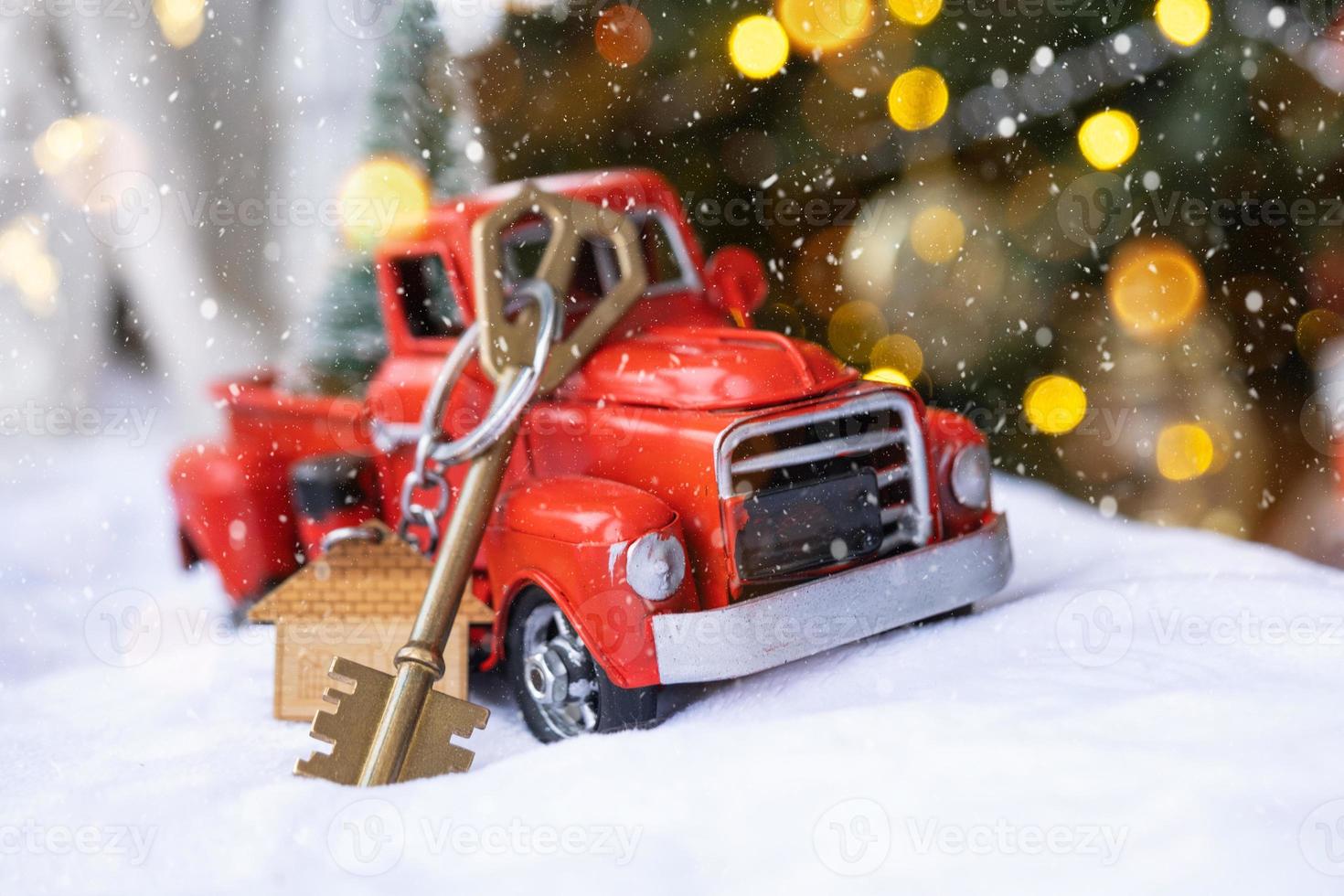 rood retro auto met een Kerstmis boom siert met de huis sleutel in de oppakken vrachtauto voor kerstmis. buying een huis, in beweging, hypotheek, lening, echt landgoed, feestelijk stemming, nieuw jaar foto