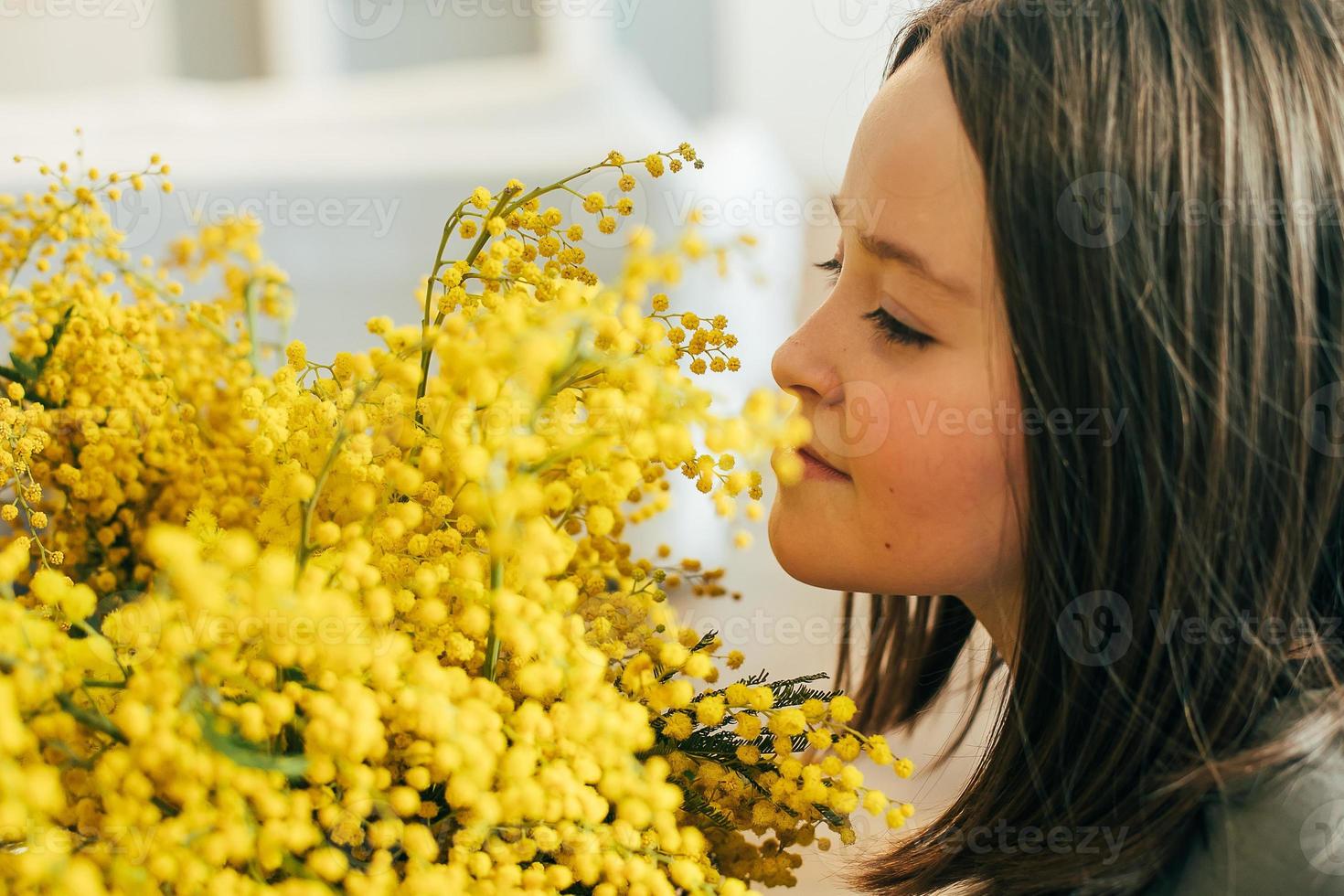 jong meisje staand met een boeket van geel mimosa en ruiken bloemen. concept van vakantie voorjaar foto